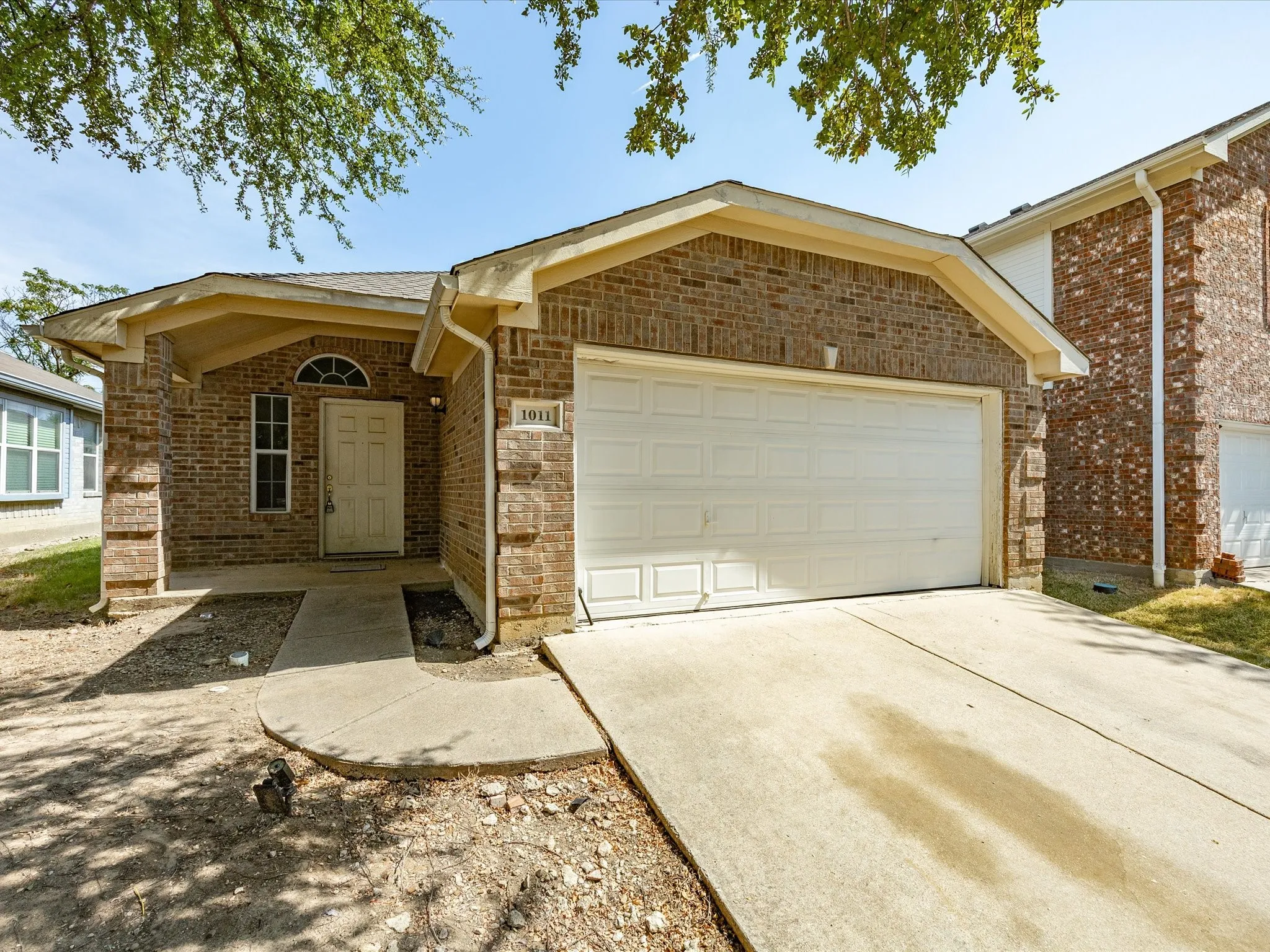 Brick exterior with attached two-car garage, concrete driveway, and covered entry