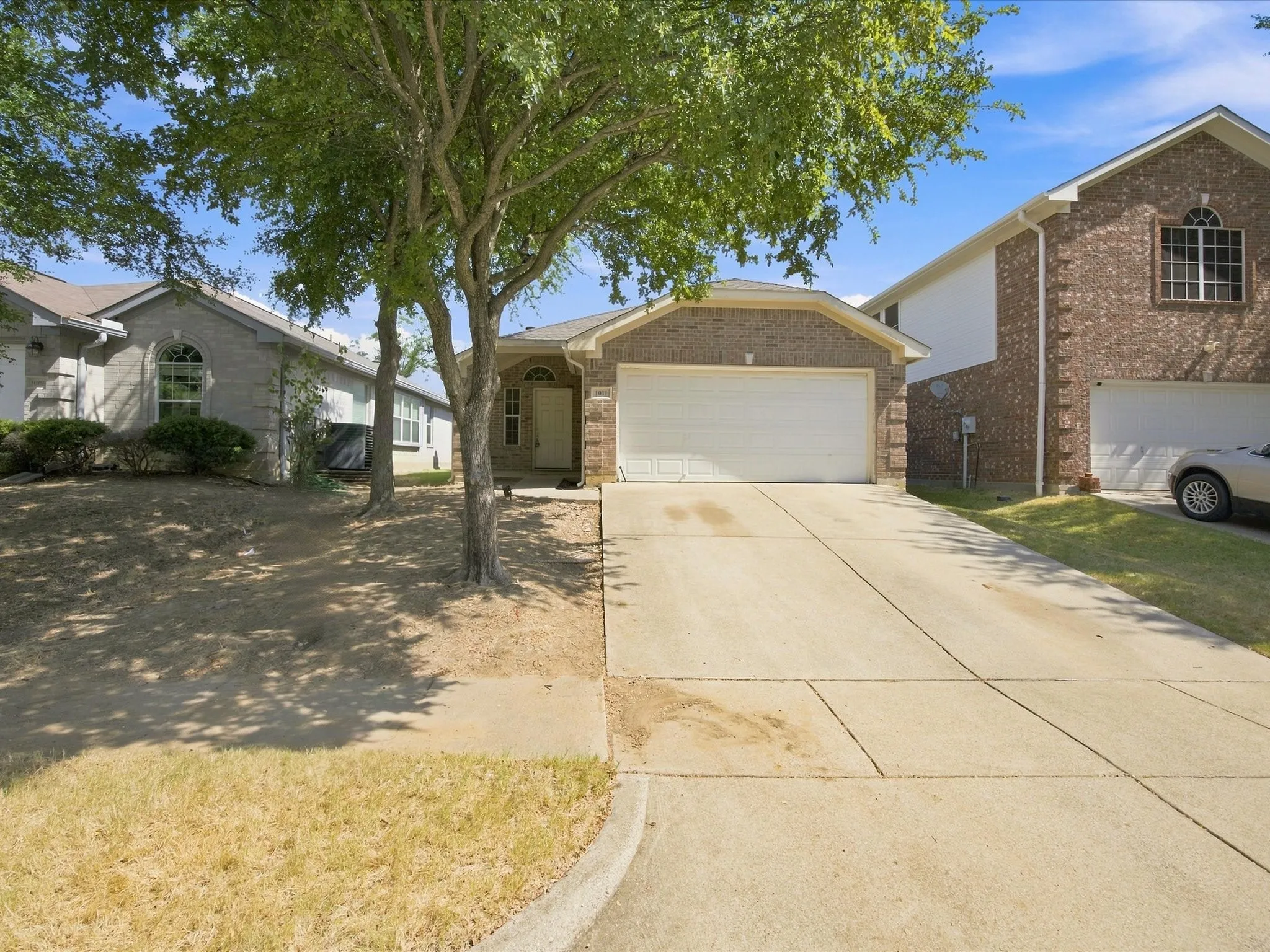 Brick-front home with an arched entry, an attached two-car garage, and a concrete driveway