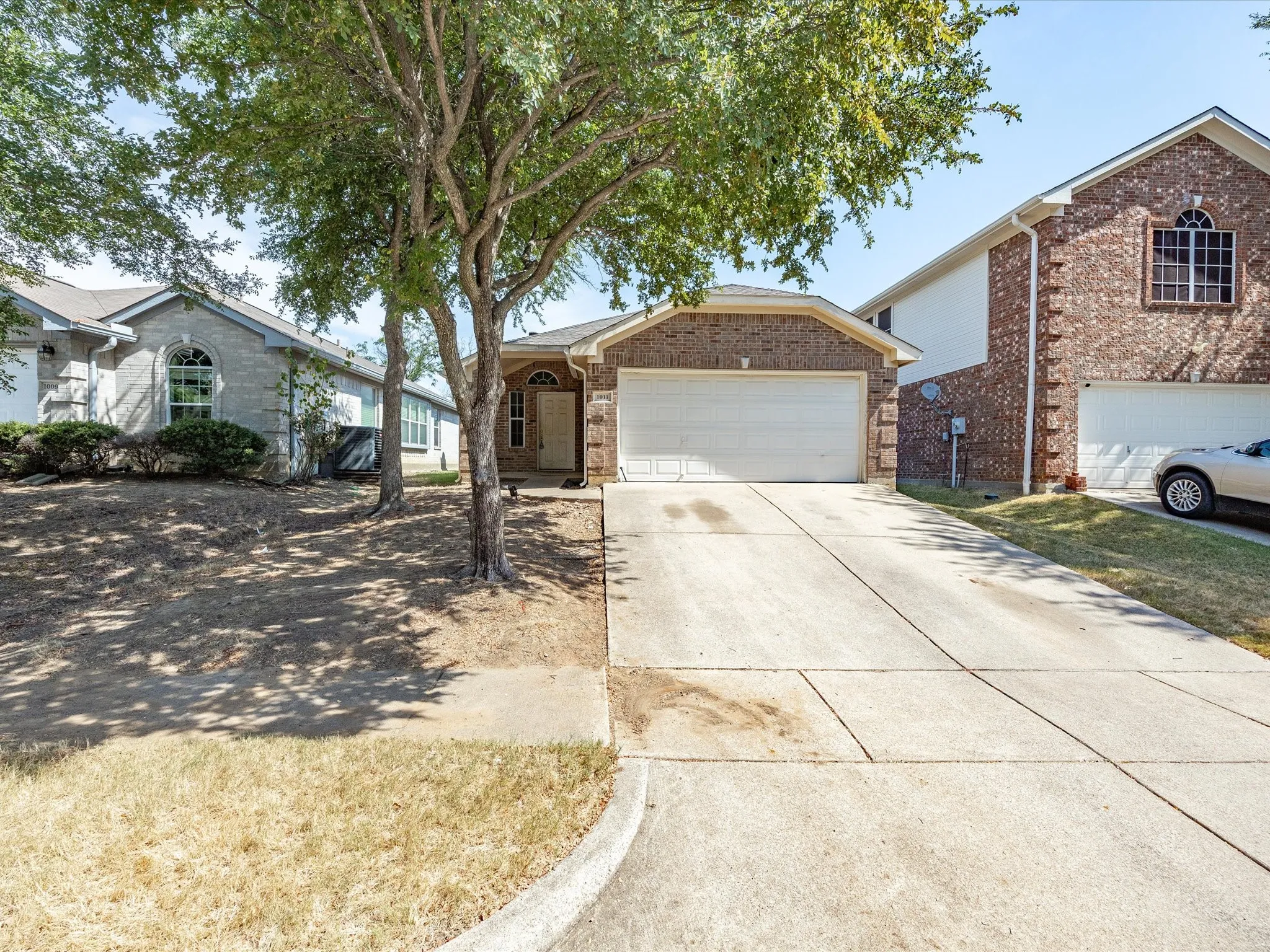 Brick facade with an arched entry, attached garage, and concrete driveway