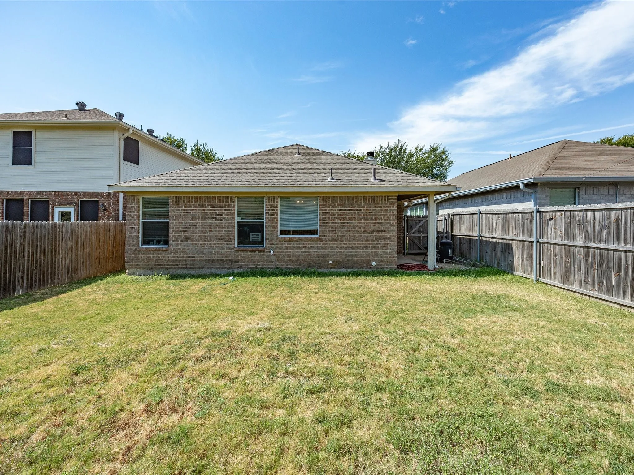 Brick exterior with covered patio and fenced backyard