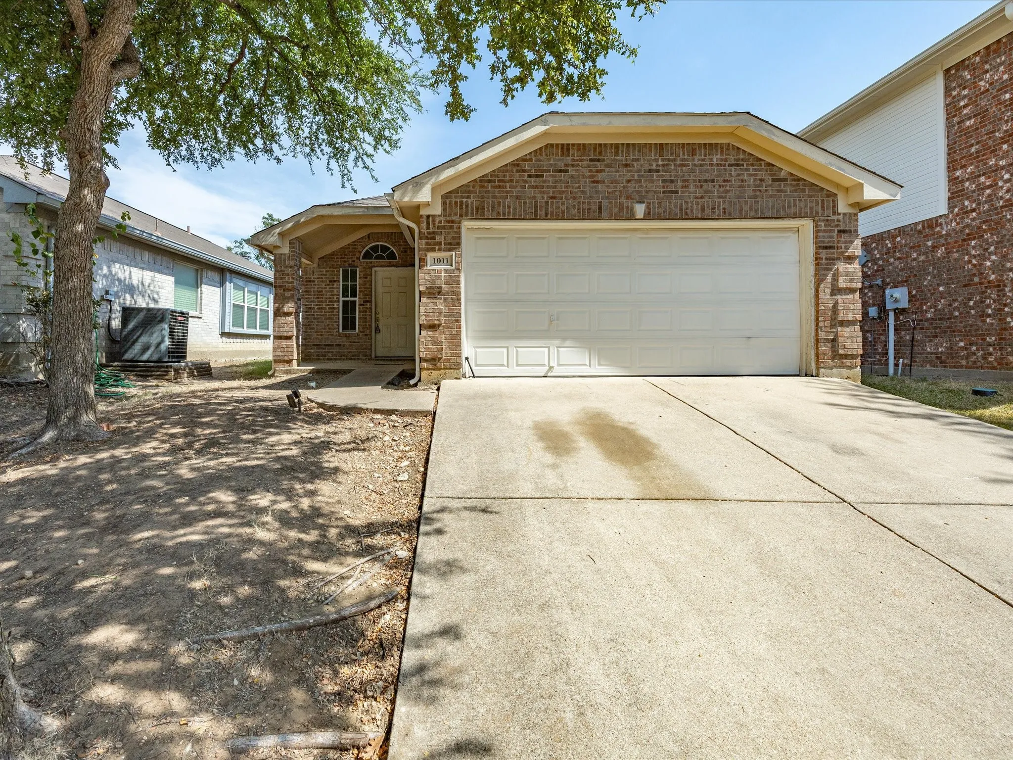 Brick facade with an attached two-car garage, concrete driveway, and covered front entry