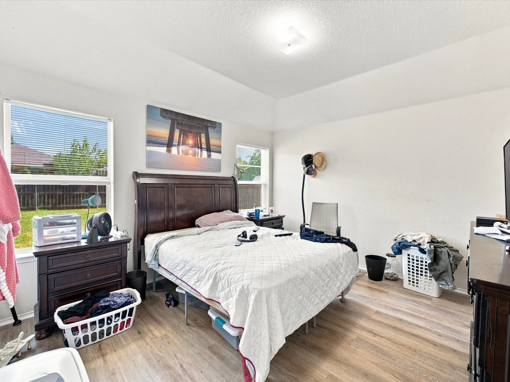 Wood-finish flooring, white walls, and a tray ceiling create an airy atmosphere