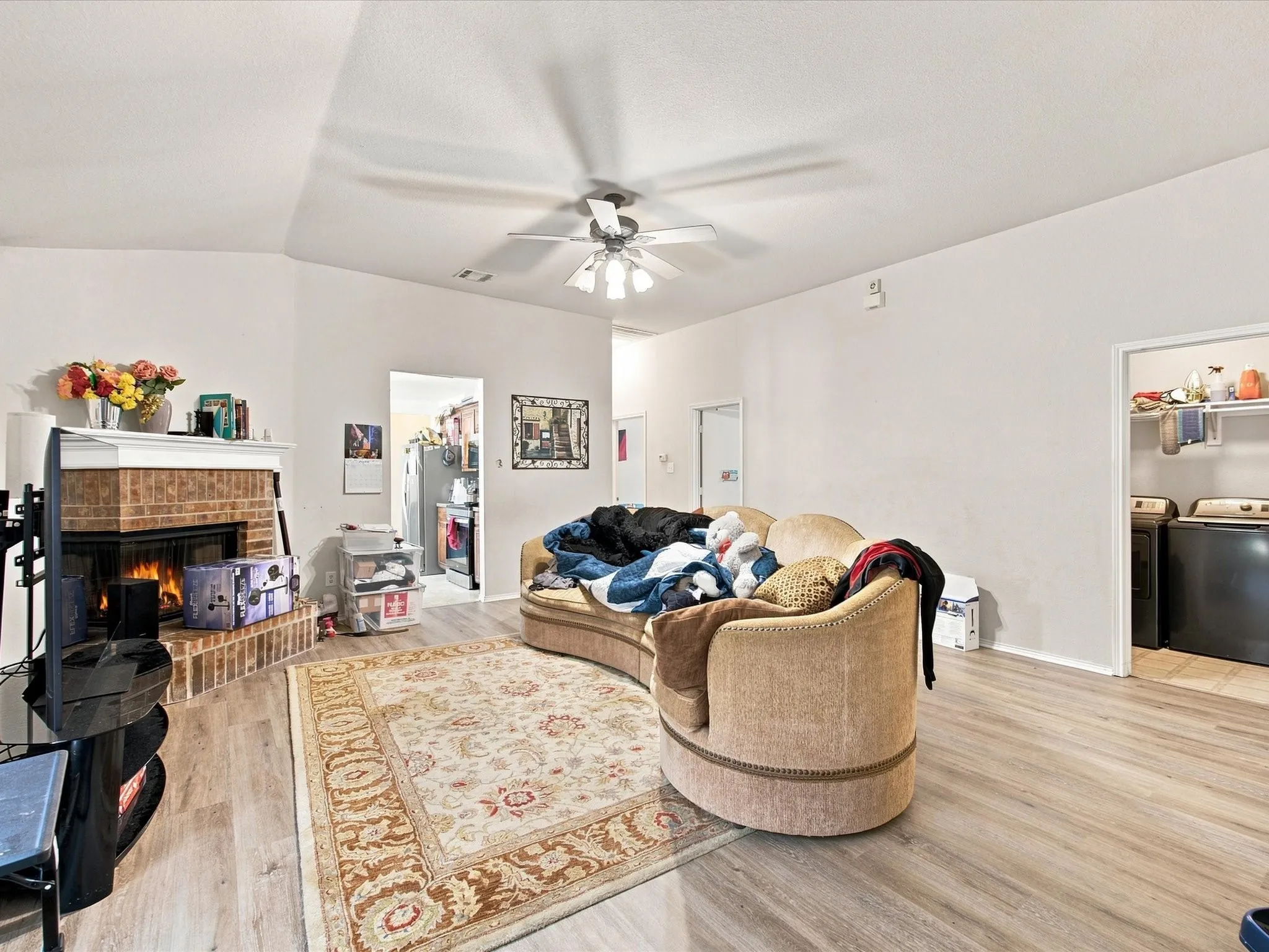Vaulted ceilings, wood-finish flooring, brick fireplace, and ceiling fan