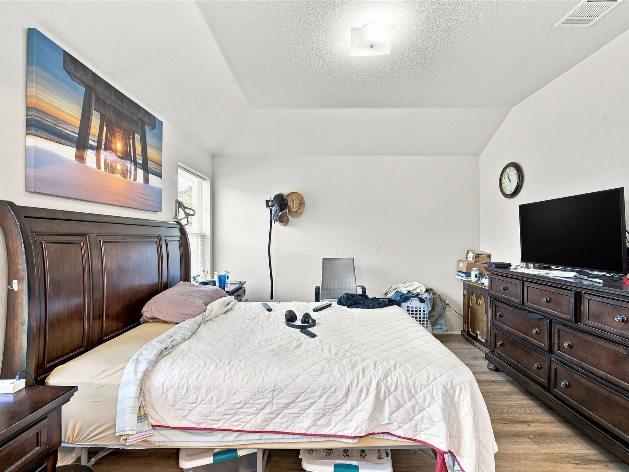Sloped ceiling, light-toned walls, wood-finish flooring, and recessed window