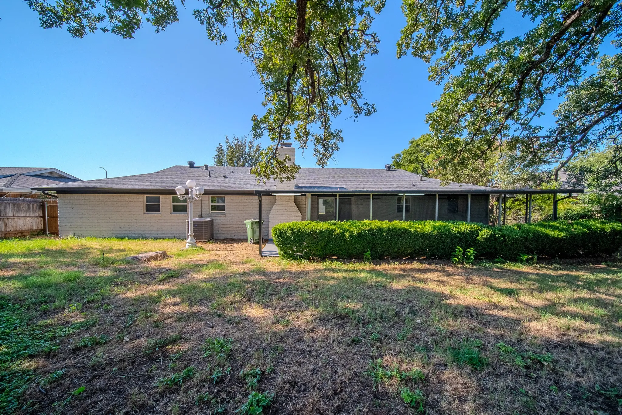 Backyard space with a covered patio, mature tree canopy, and established perimeter hedging
