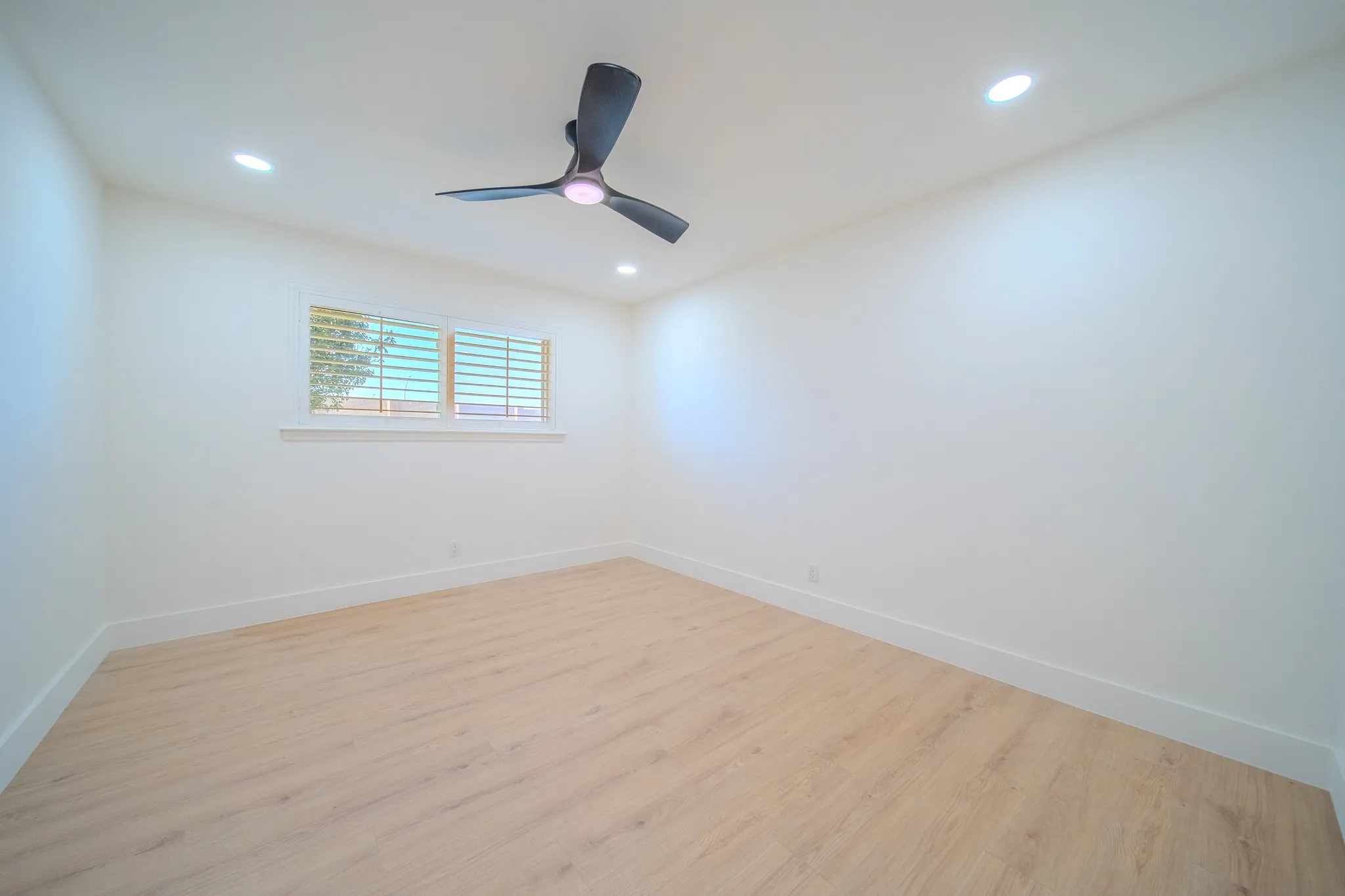 Recessed ceiling lighting, modern ceiling fan, wood-finish flooring, white walls, and window with horizontal blinds