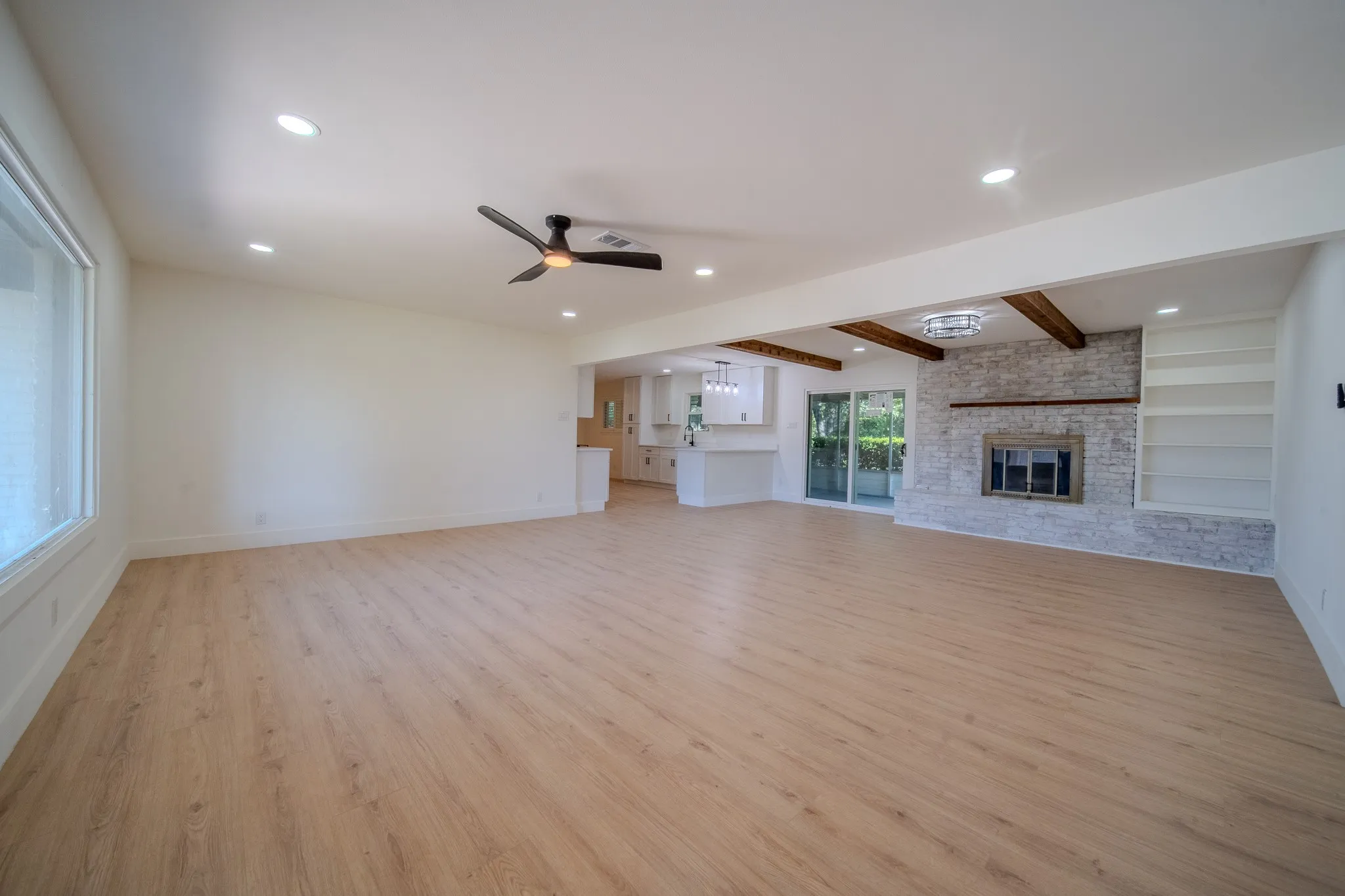 Expansive main living area with wood-finish flooring, recessed lighting, and a modern ceiling fan