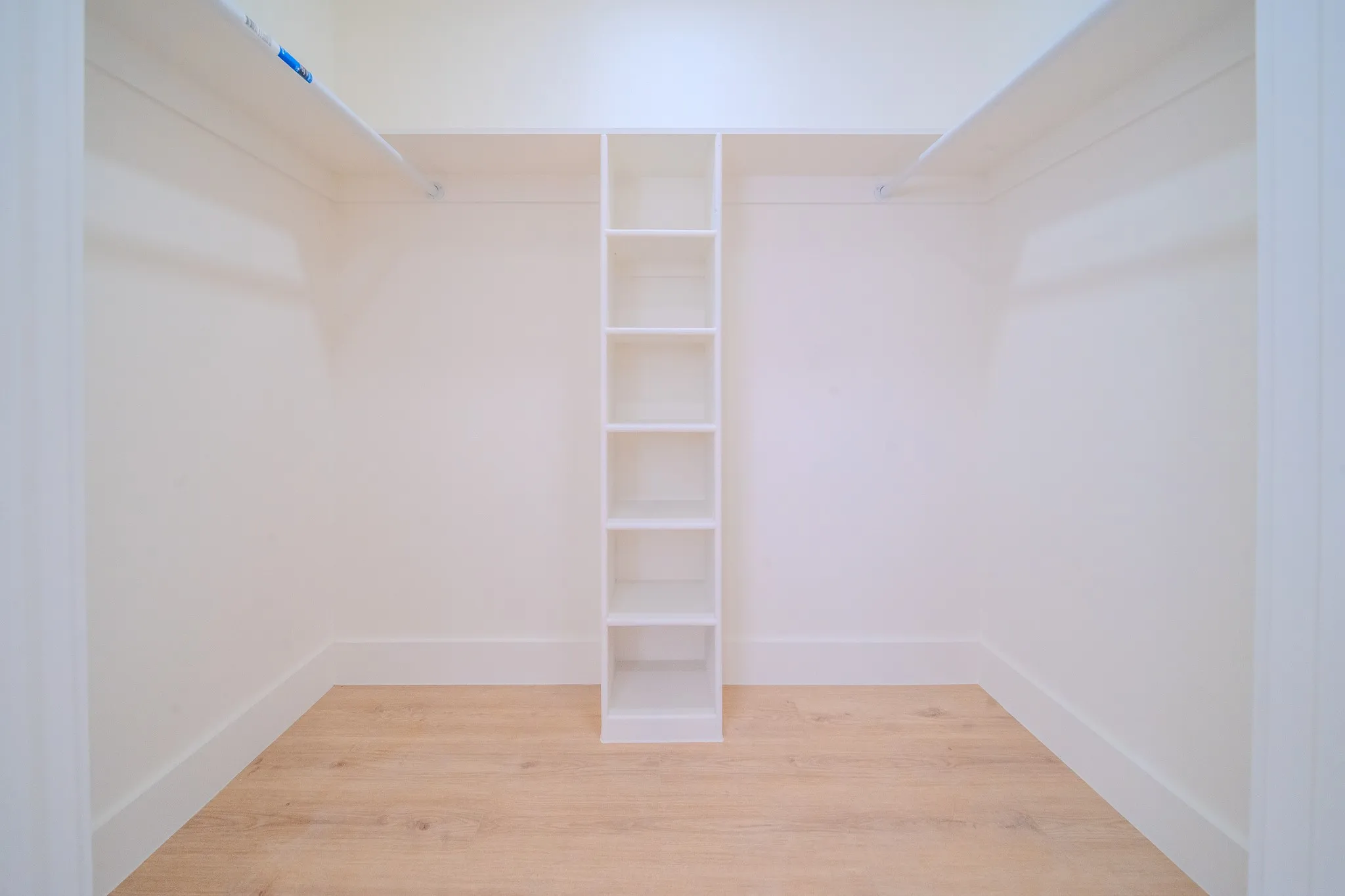 Built-in shelving, wood-finish flooring, and white walls create a functional storage space