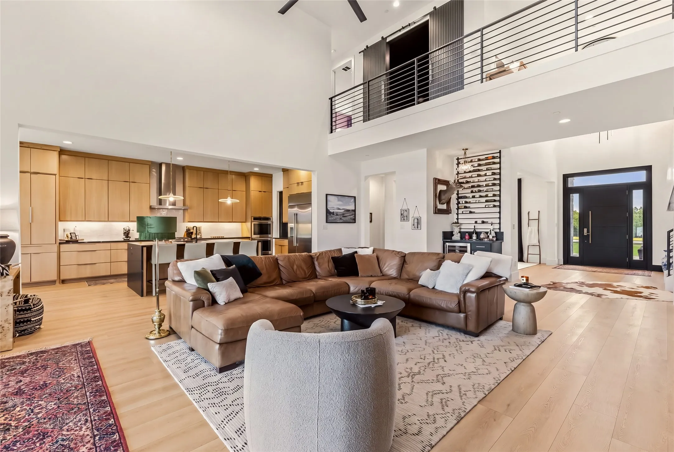 Expansive open-concept living space with two-story ceilings and a modern kitchen featuring wood cabinetry and an island