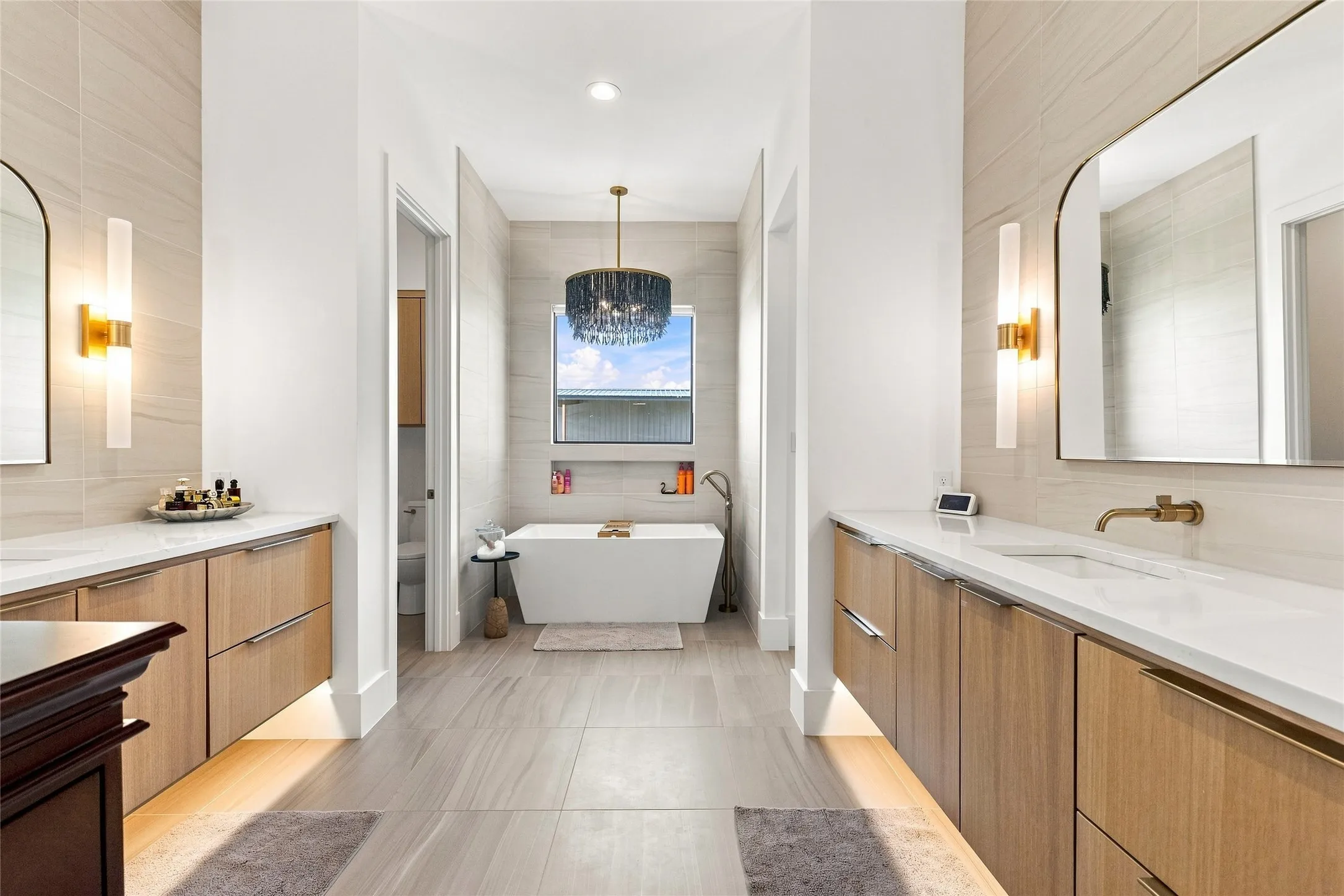 Dual vanities with rift-sawn white oak cabinetry, white countertops, floor to ceiling tile behind vanities and around the tub, and a custom fully tiled shower with dual heads