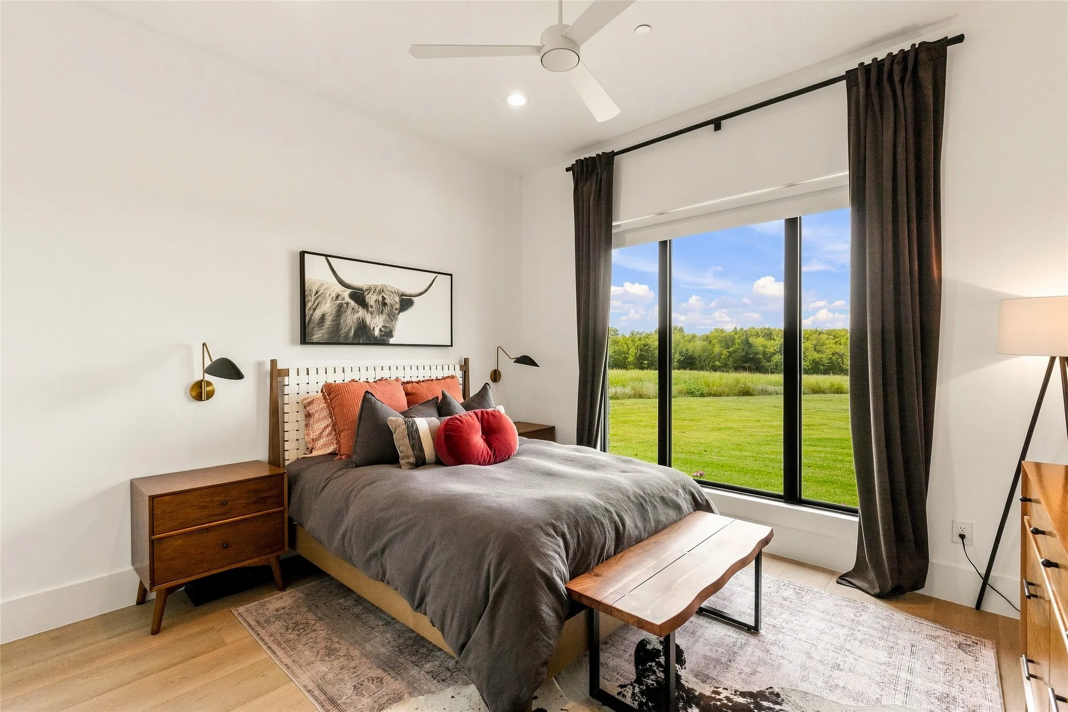 Expansive window with black trim, LVP, white walls, and a ceiling fan