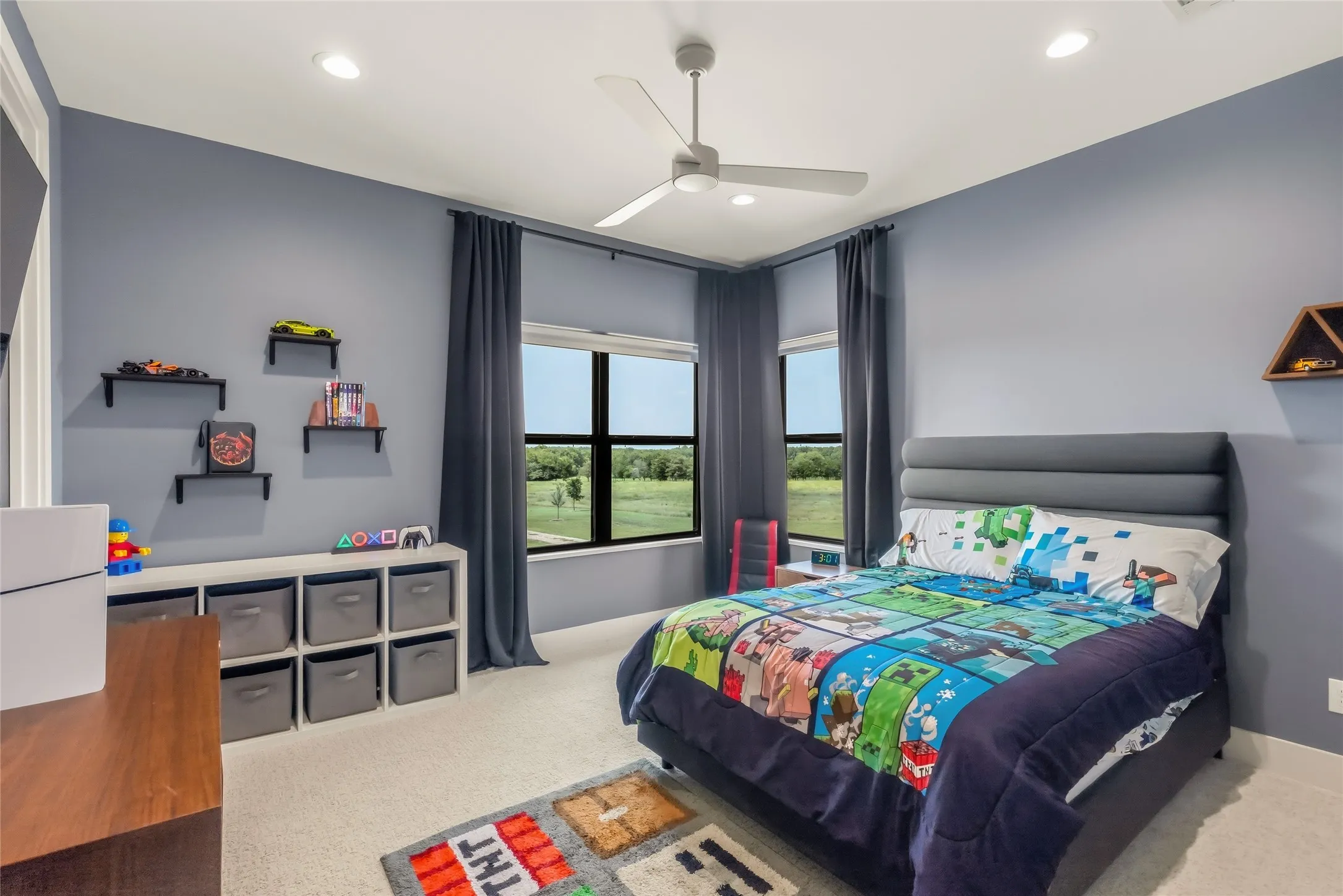 Recessed ceiling lighting, ceiling fan, wall-mounted shelving, large windows, and carpet flooring