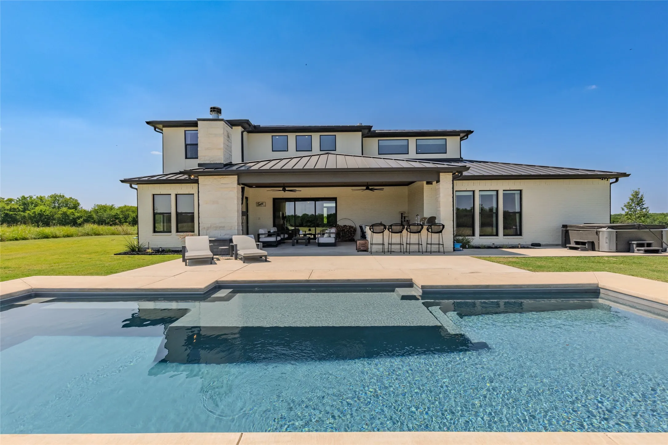 Modern exterior with a pool, hot tub, and expansive patio
