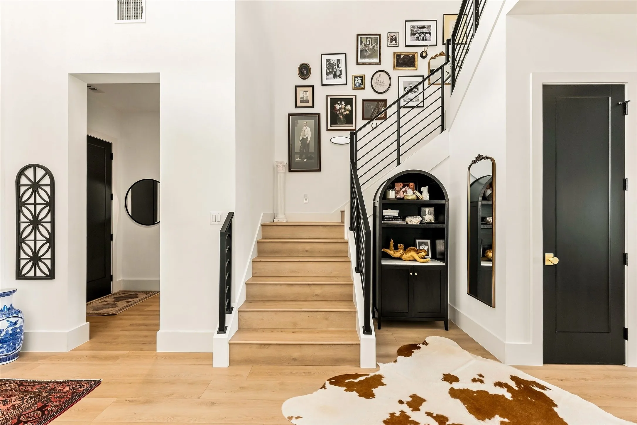 Light LVP, a contemporary staircase with black metal railings, and a large storage closet under the stairs