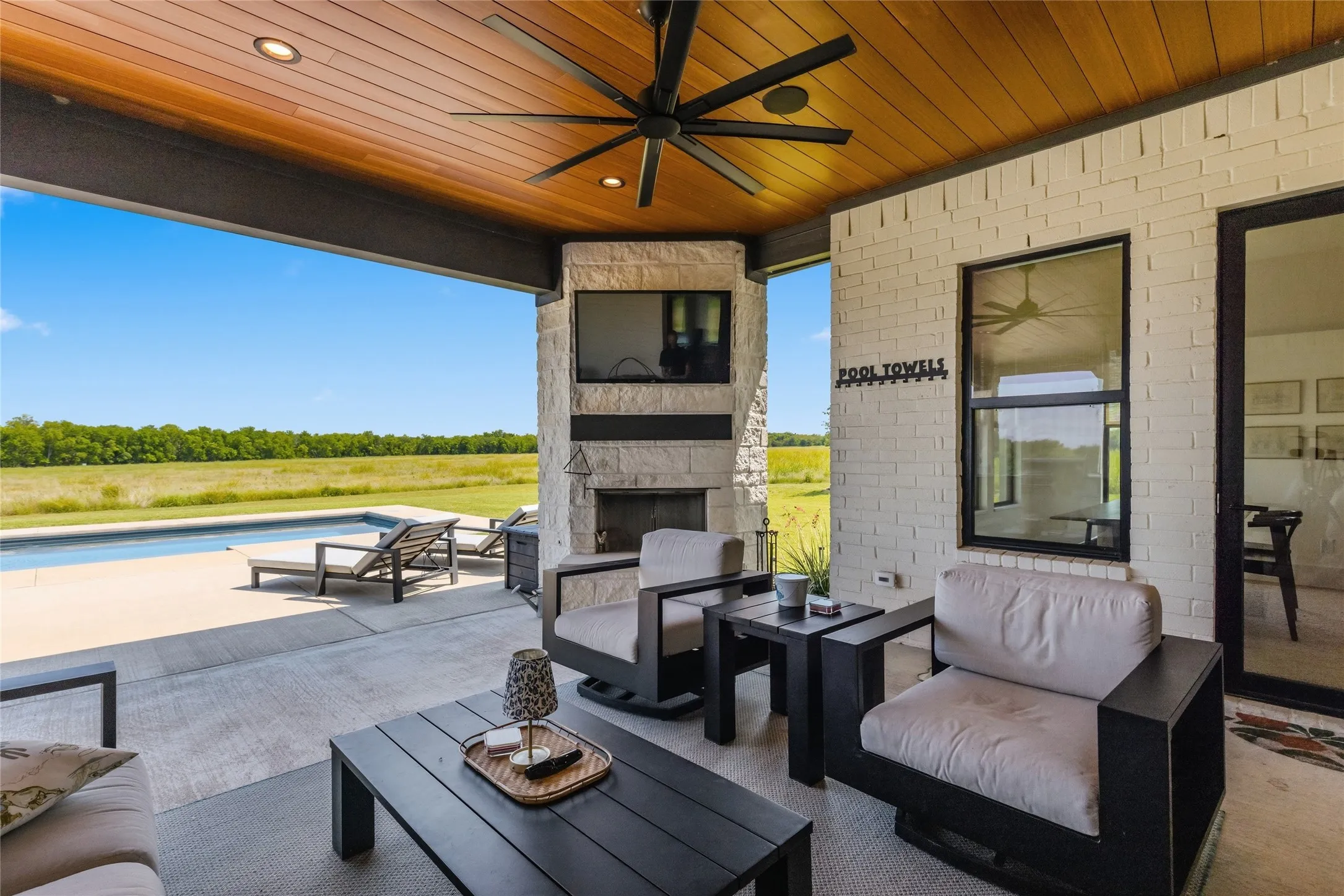 Covered outdoor patio with a wood-finish ceiling, recessed lighting, ceiling fan, and stone-clad fireplace