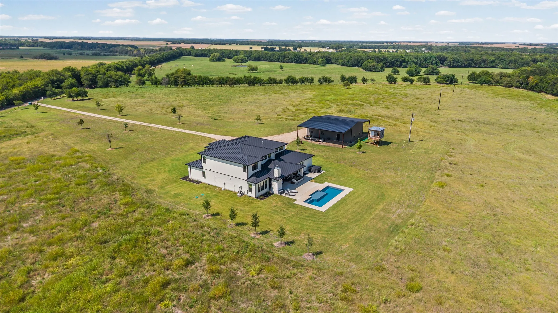 Expansive 163ac property featuring a modern residence, detached structure, and an in-ground swimming pool