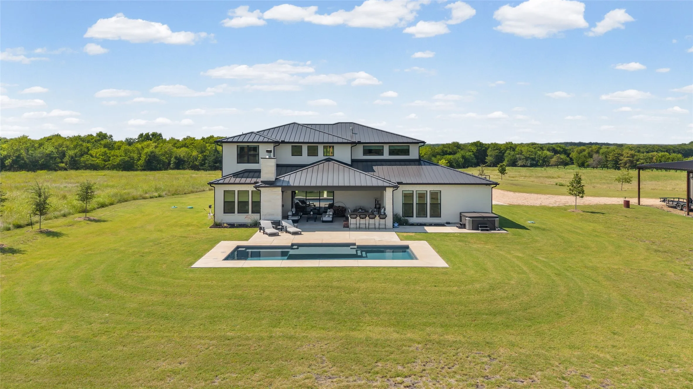 Contemporary residence featuring a black standing seam metal roof and light-colored exterior