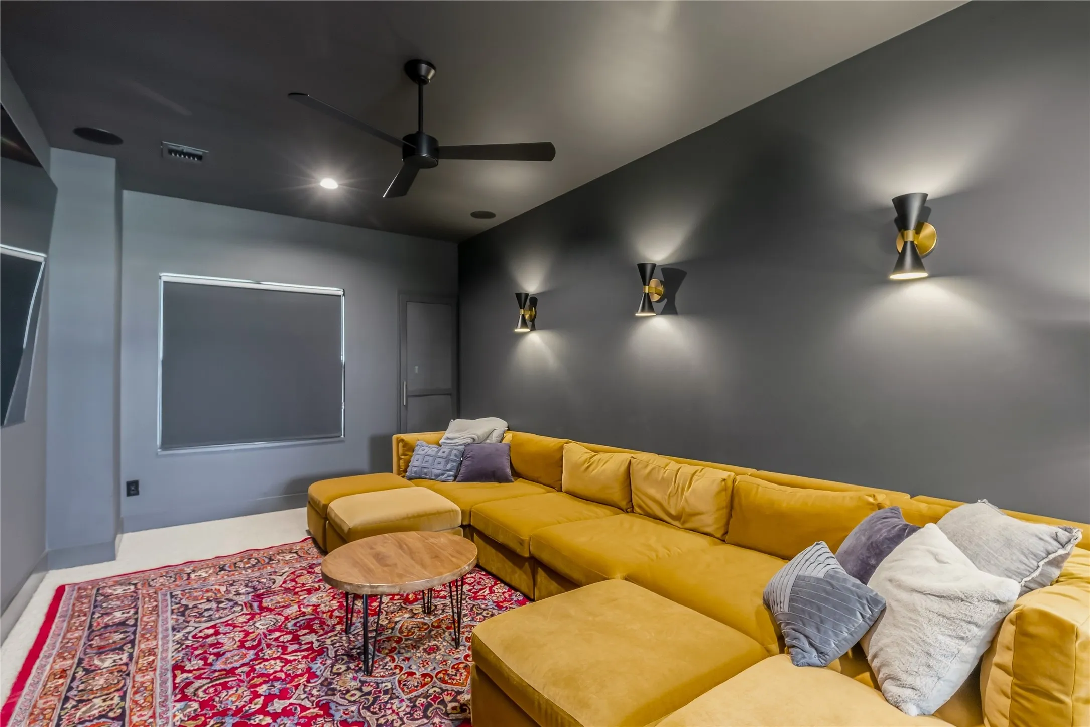 Recessed ceiling lighting, wall-mounted sconces, ceiling fan, and window with roller shade