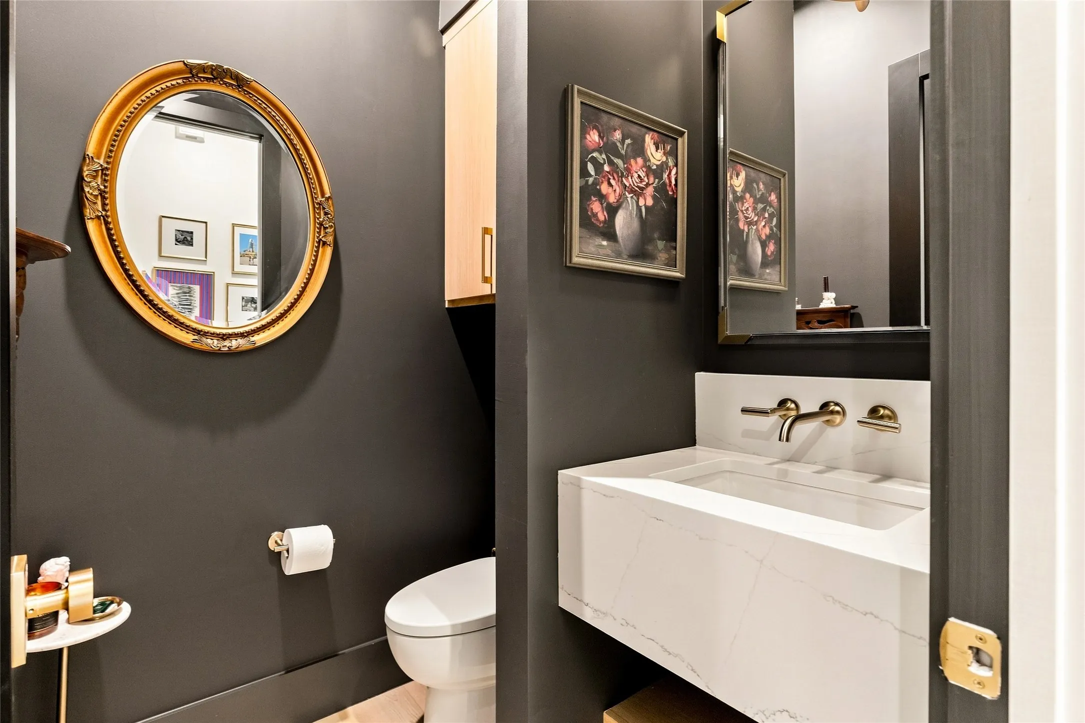 Powder bath off living area has floating vanity with integrated basin and wall-mounted gold-tone faucet