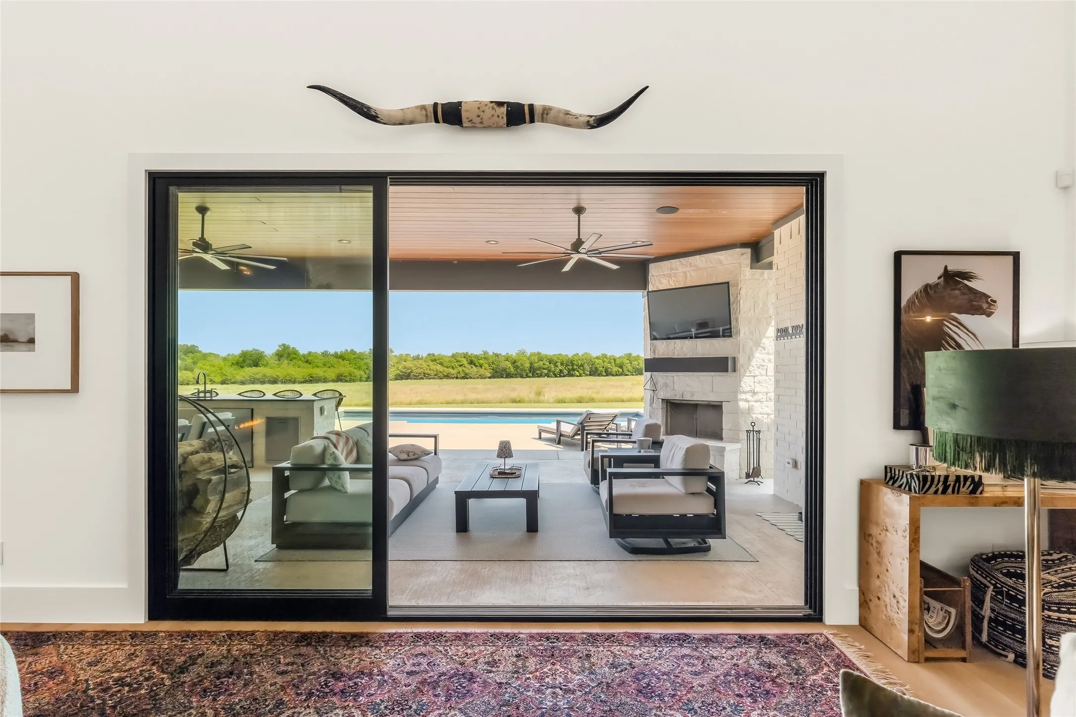 Expansive outdoor living area featuring a stone-clad fireplace, integrated outdoor kitchen, and a swimming pool