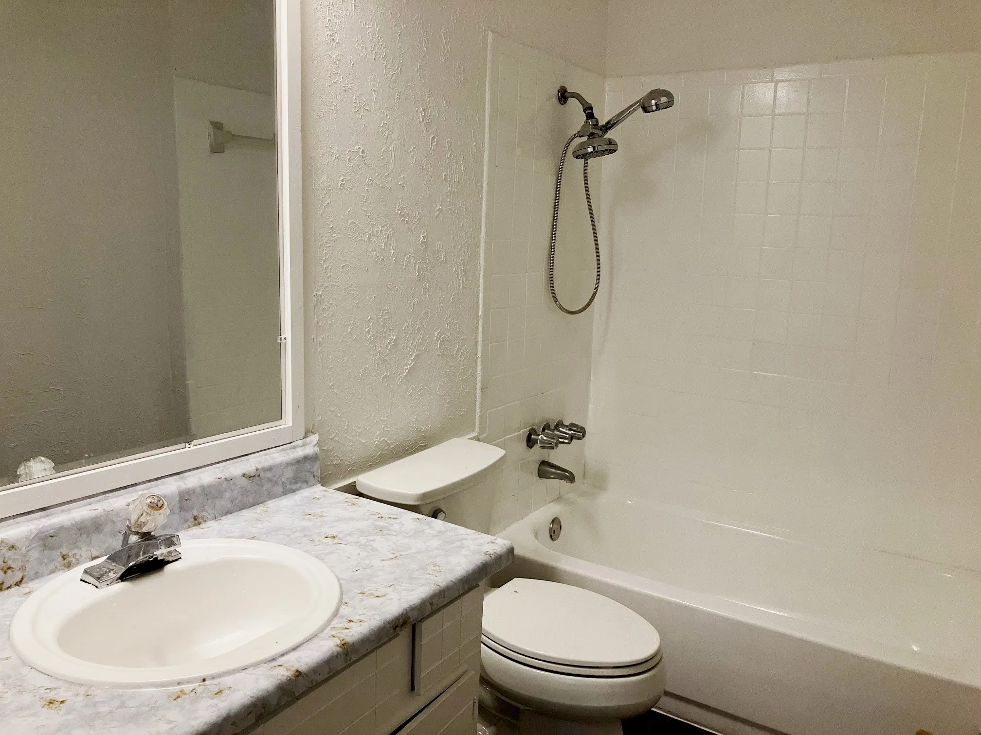 Bathtub with a shower fixture, wall-mounted mirror, and vanity with a countertop and undermount sink