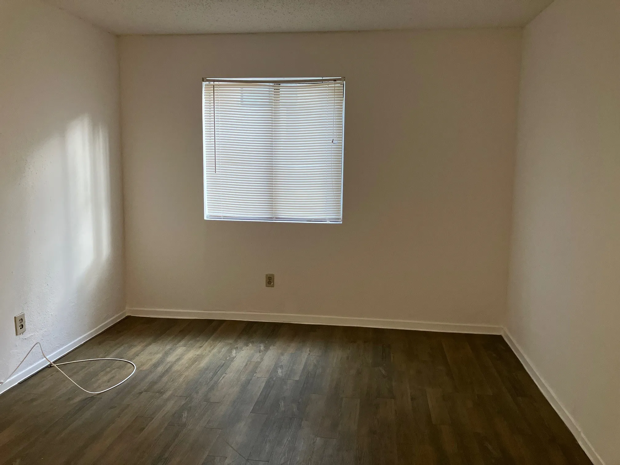 Wood-finish flooring with white baseboards and light-toned walls