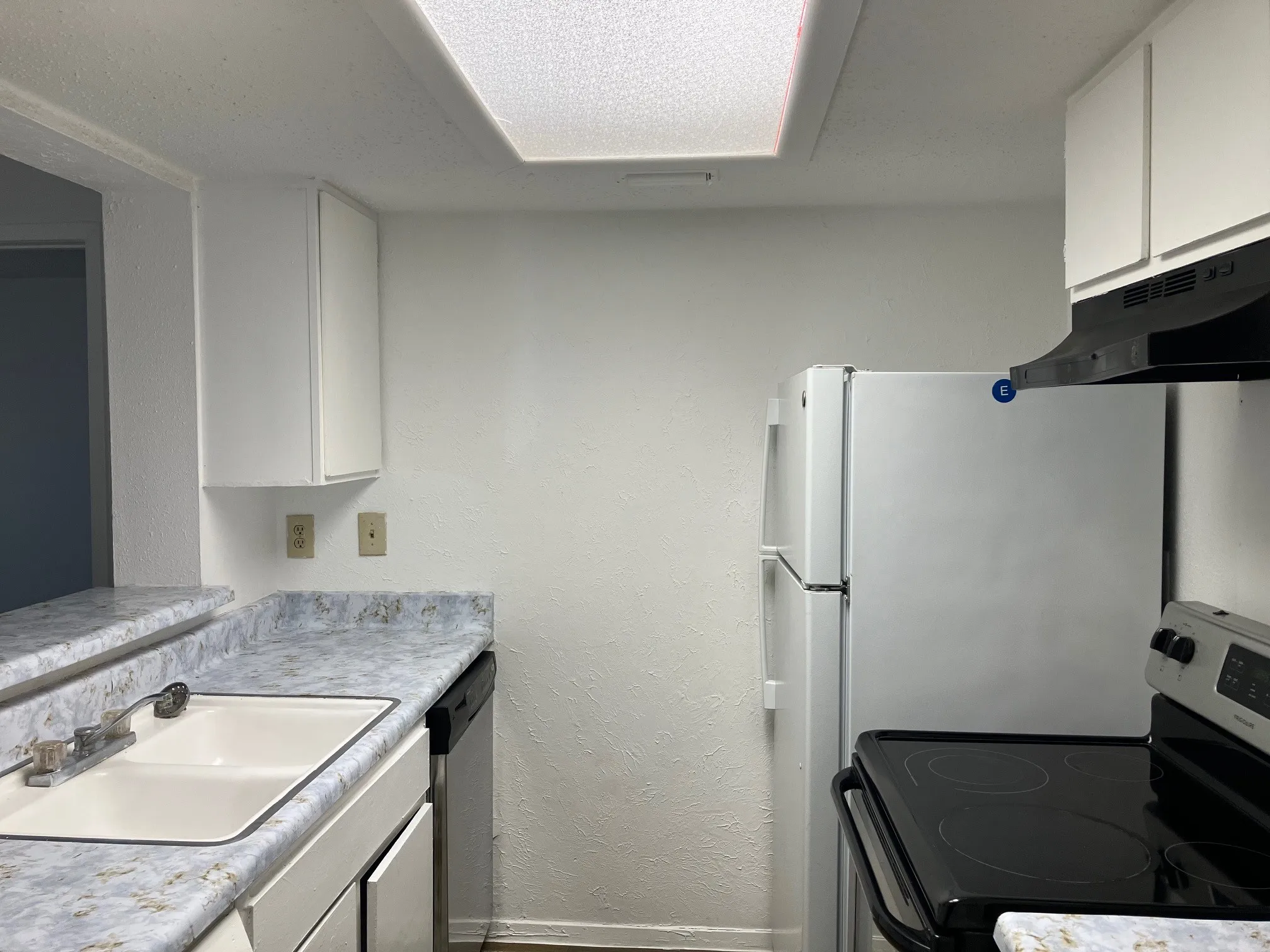 Kitchen featuring white cabinetry, a dual-basin sink, a dishwasher, and a built-in range with an overhead microwave