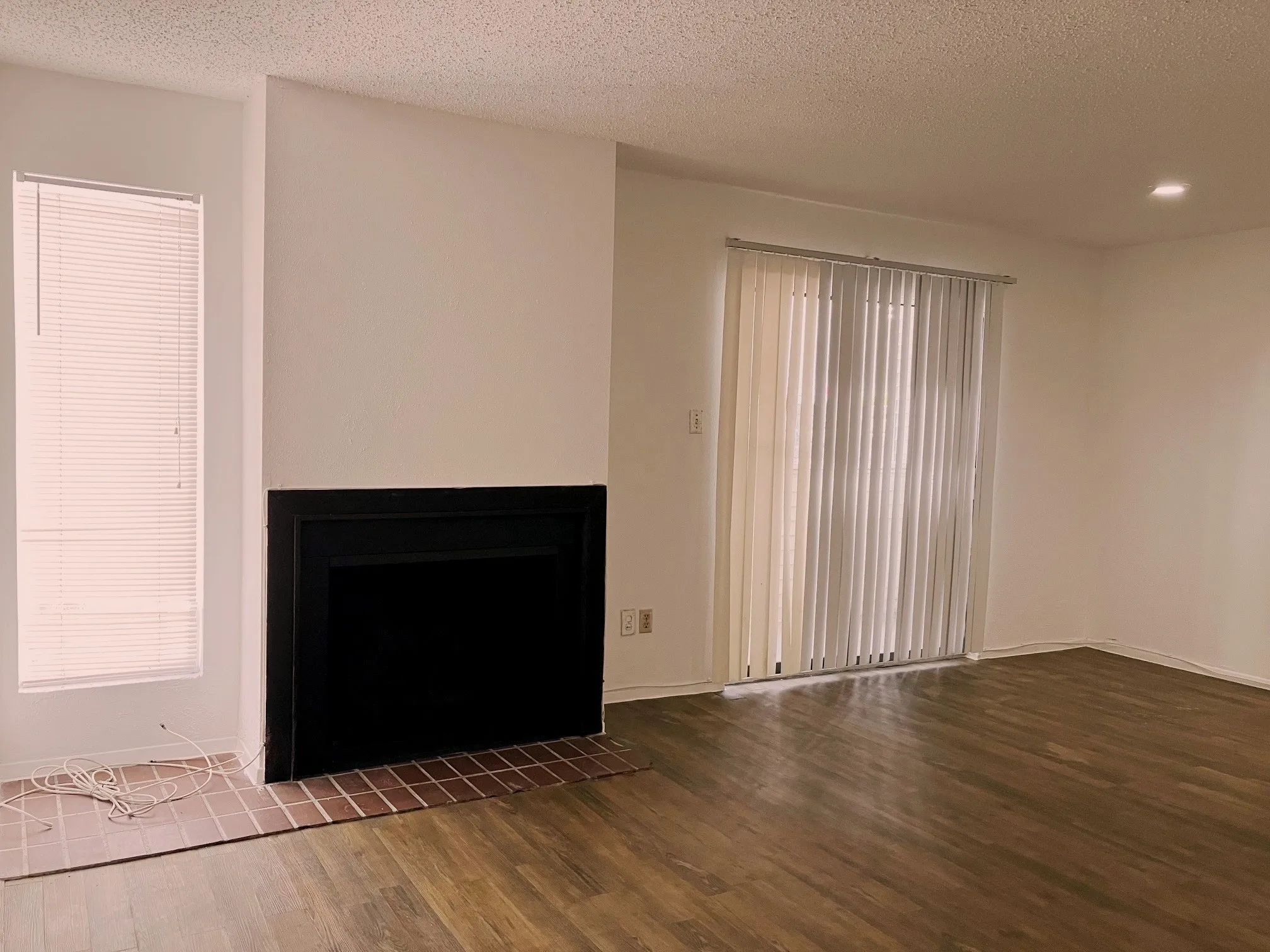 Wood-finish flooring, recessed lighting, and a fireplace with a tiled hearth
