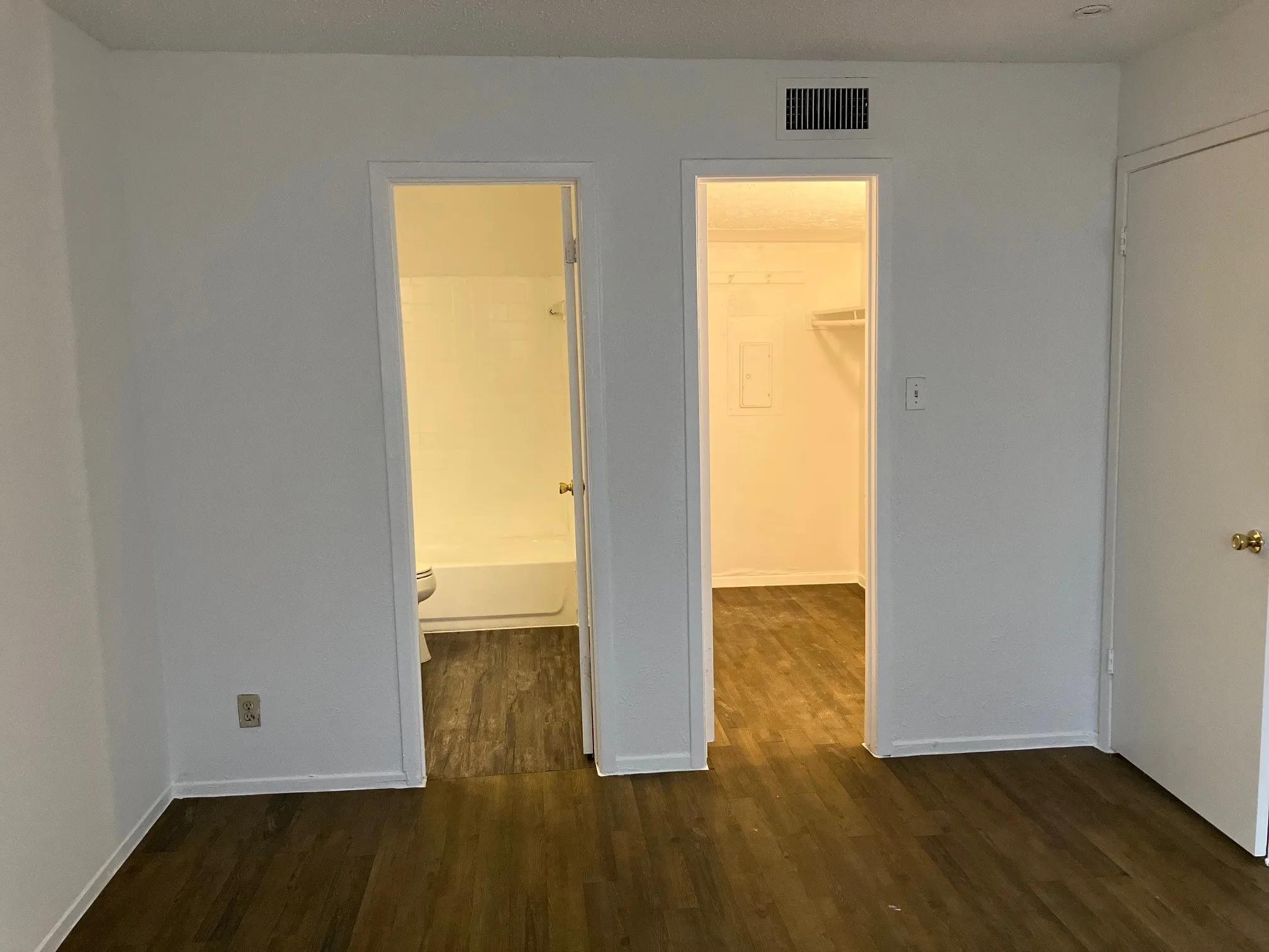 Wood-finish flooring throughout, bright white walls, and a recessed ceiling light