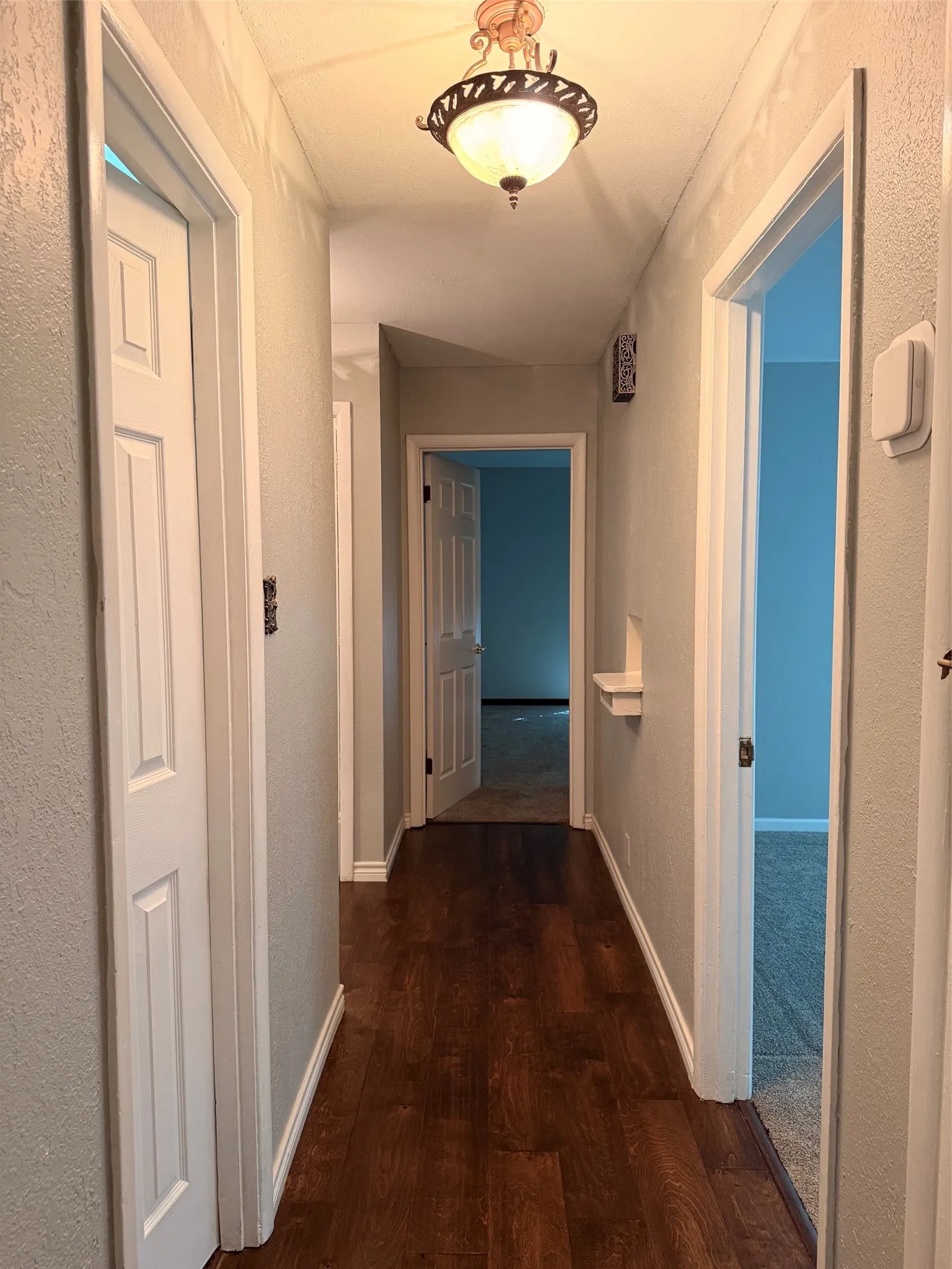 Hallway featuring wood-finish flooring, recessed lighting, and a decorative ceiling fixture and phone niche