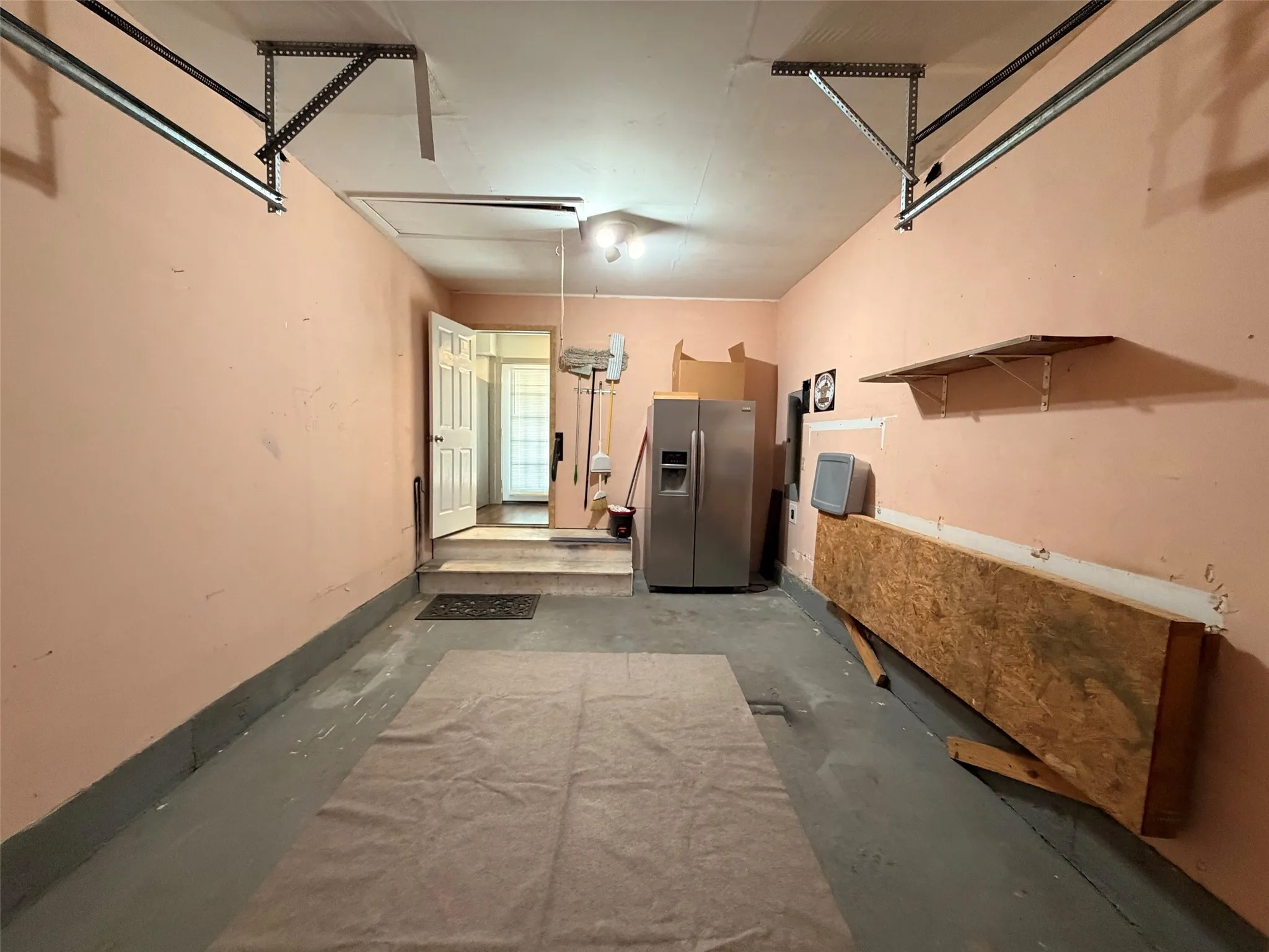 Attached garage space with painted concrete flooring and second refrigerator
