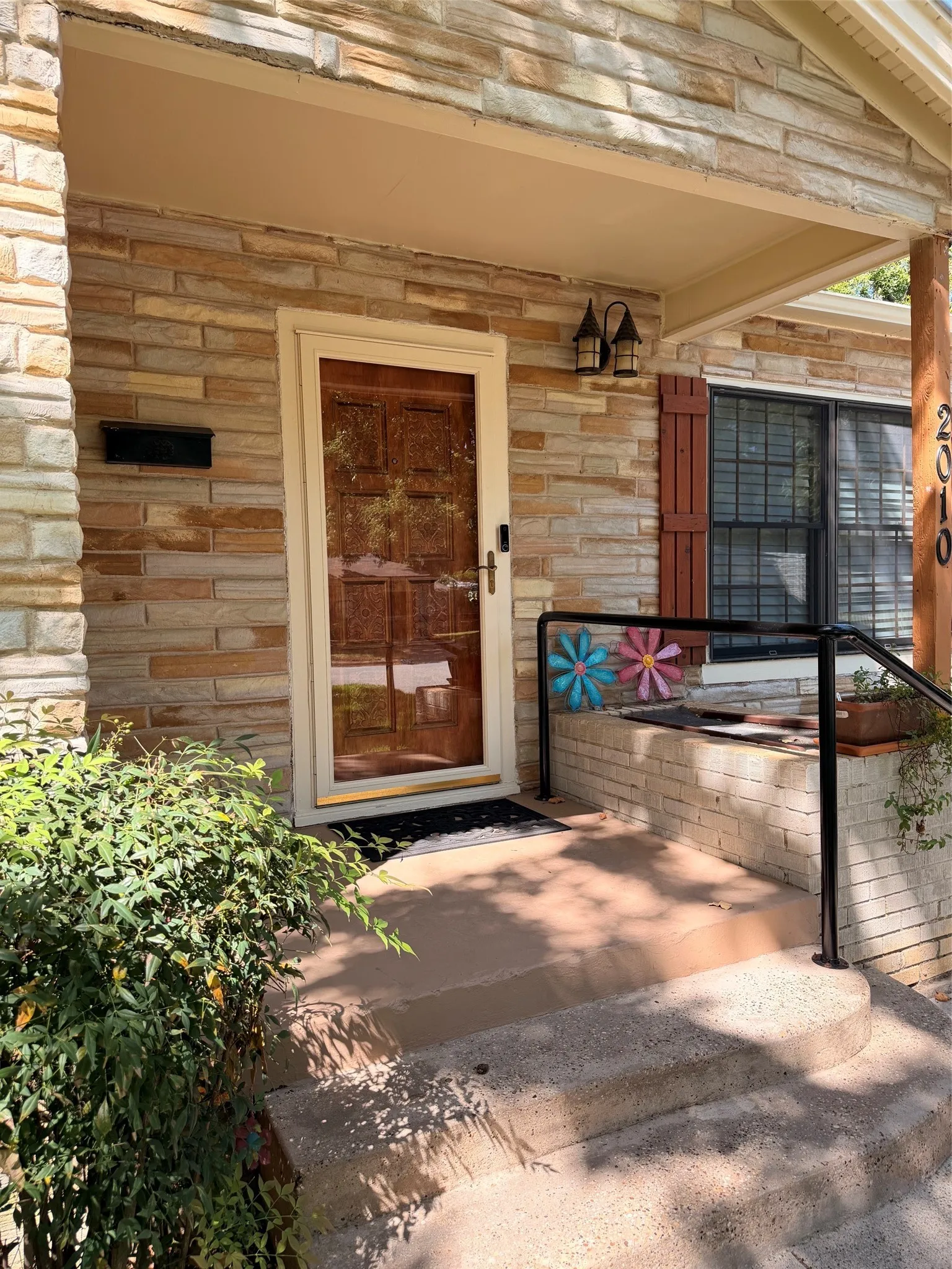 Stone veneer exterior with a covered porch featuring dual outdoor sconces