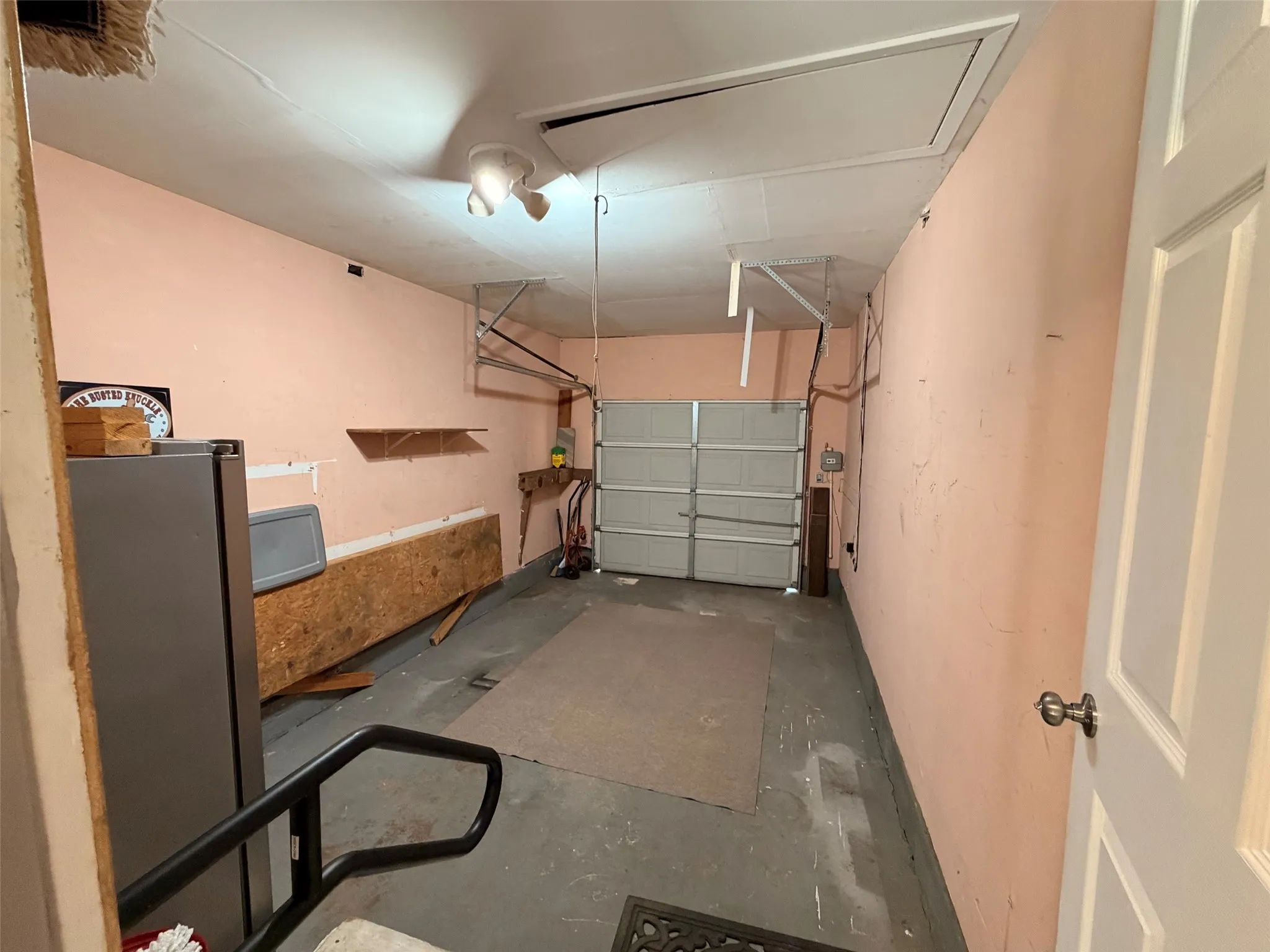 Attached garage space with painted concrete flooring and second refrigerator