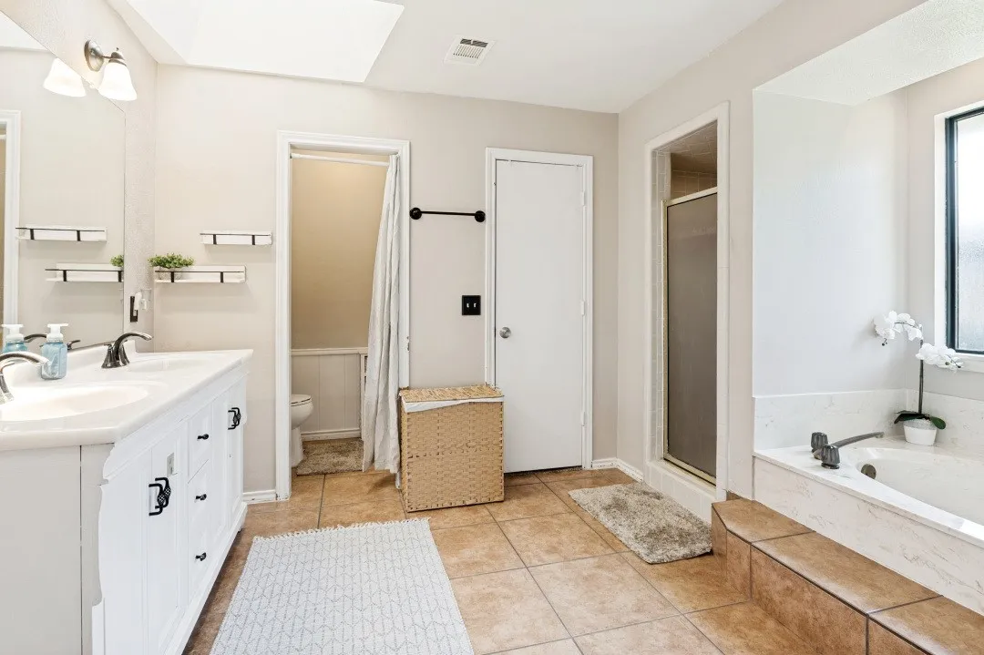 Dual vanity with undermount sinks, bronze finish faucets, and white cabinetry