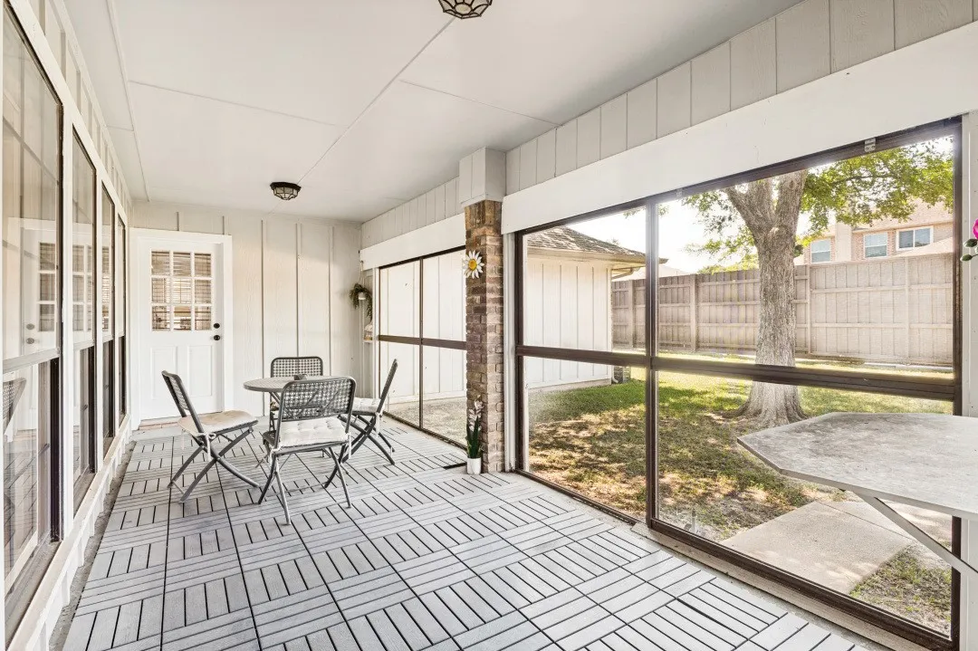 Screened porch featuring light-toned flooring, white paneling, and a full-light entry door
