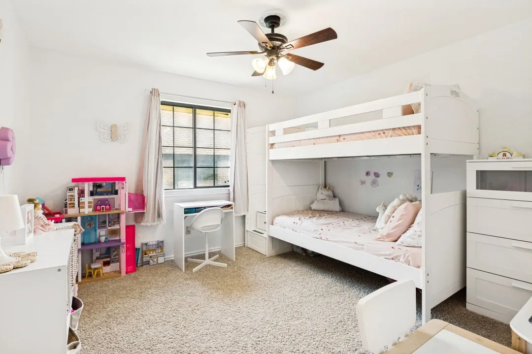Window with gridded panes, ceiling fan with light fixture, light-toned carpet flooring, white walls