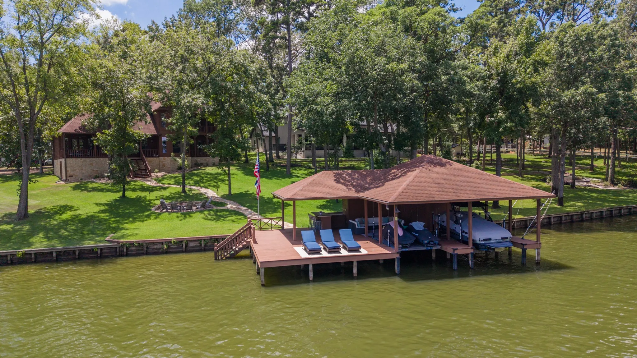 Waterfront property featuring a private boat dock with covered slips, an expansive deck area, and direct water access