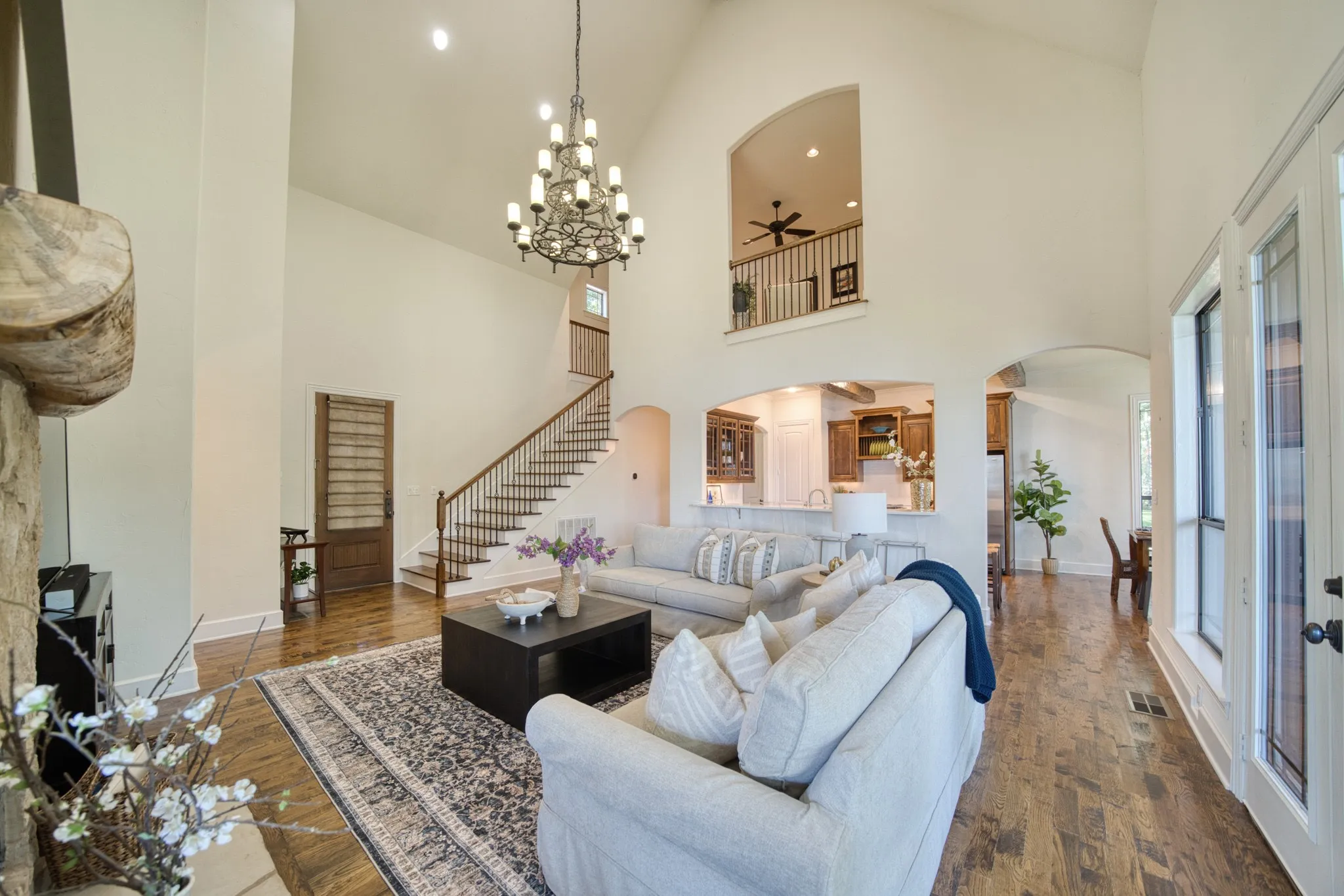 Vaulted ceilings with an ornate chandelier, rich wood-finish flooring, and an open concept layout