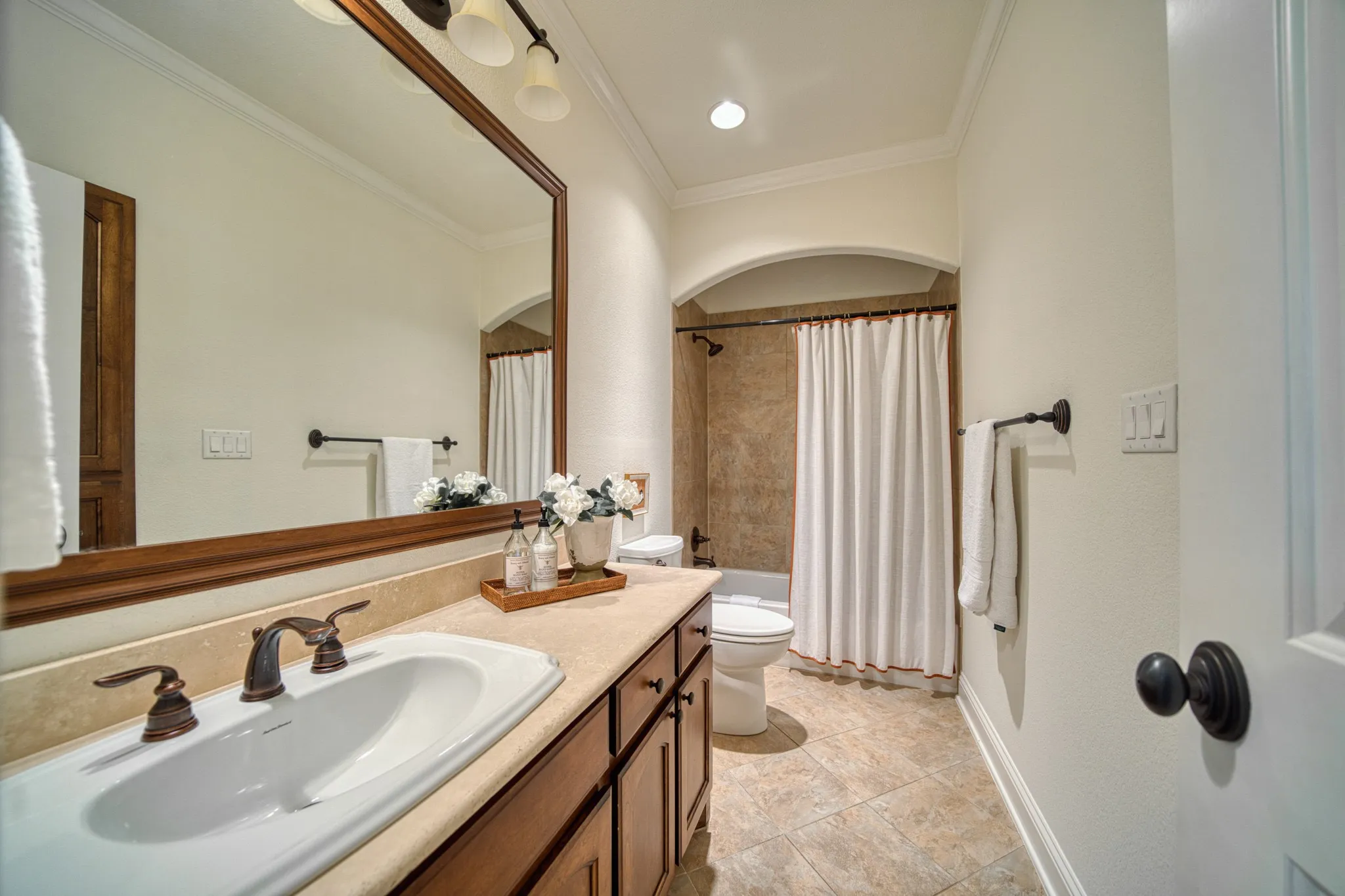 Single vanity with an integrated sink and bronze-finish faucet, framed mirror, recessed lighting, and tile flooring