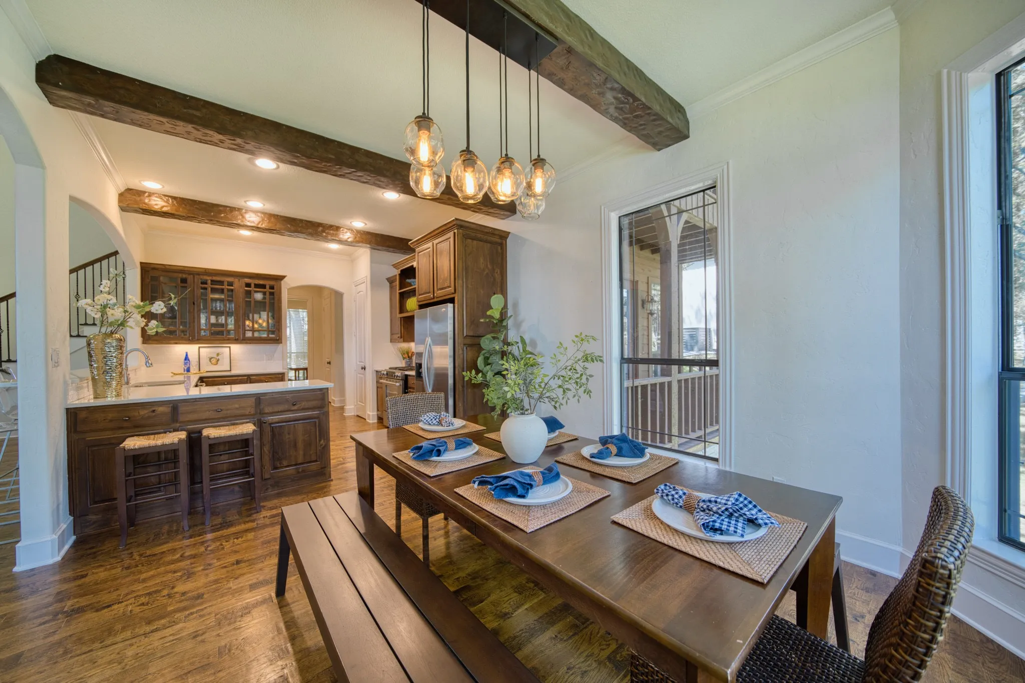 Wood-finish flooring, exposed ceiling beams, recessed lighting, built-in cabinetry, and a multi-bulb pendant light fixture
