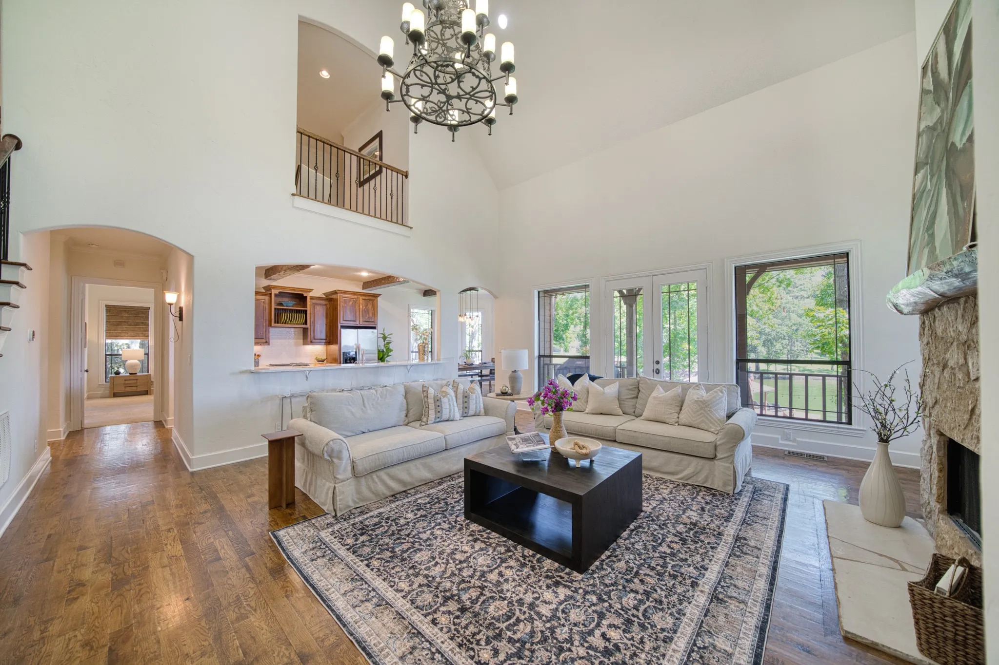 Vaulted ceilings, wood-finish flooring, stone fireplace, open archways, and a multi-level layout