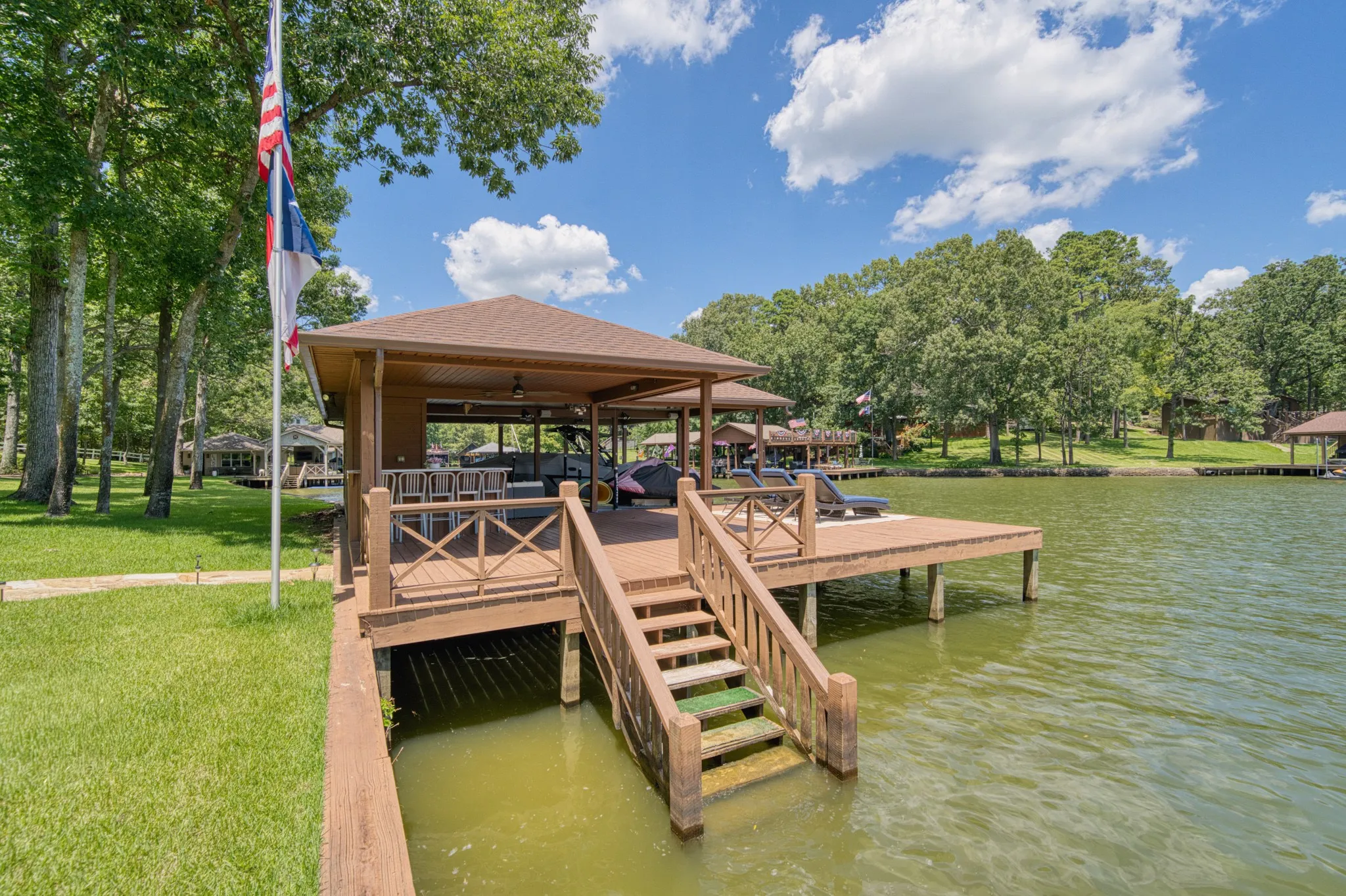 Covered dock with boat slips, built-in bar area, expansive open-air deck space, and direct water access