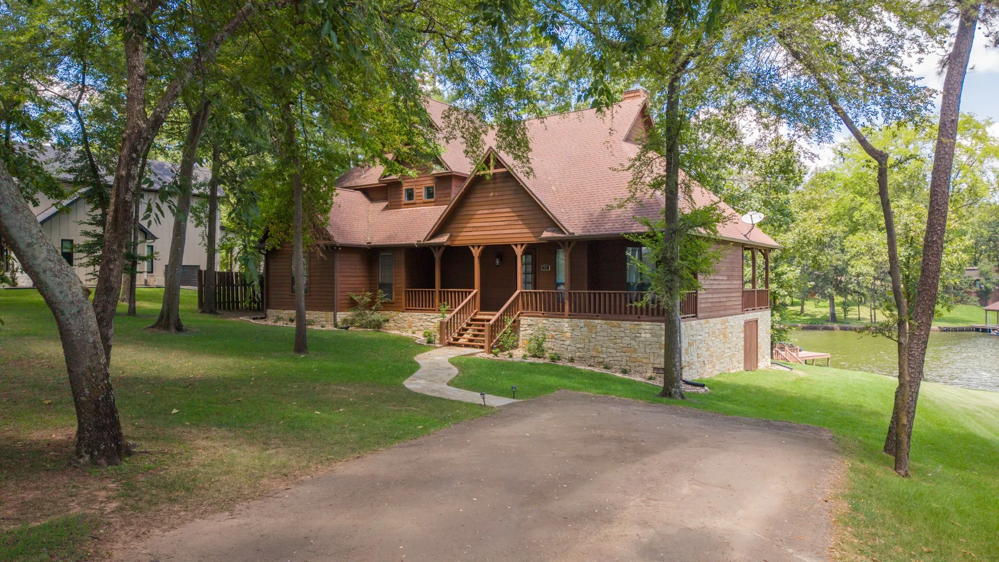 Wood-sided exterior with a stone foundation, a covered porch, and a private dock on the water