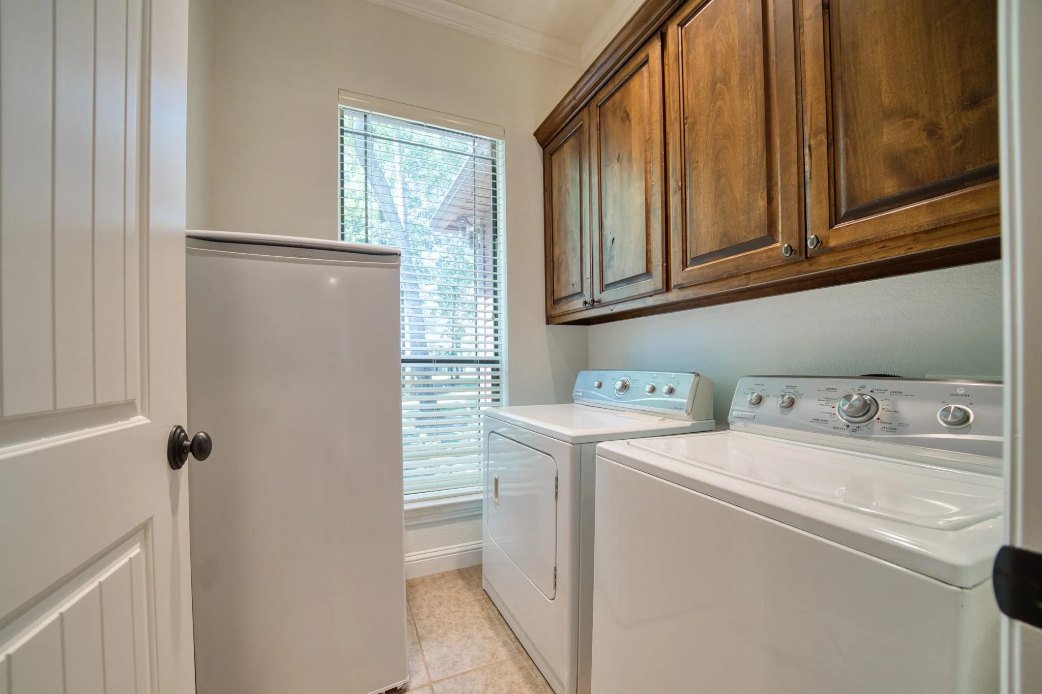 Built-in wood cabinetry, tiled flooring, and a window with blinds