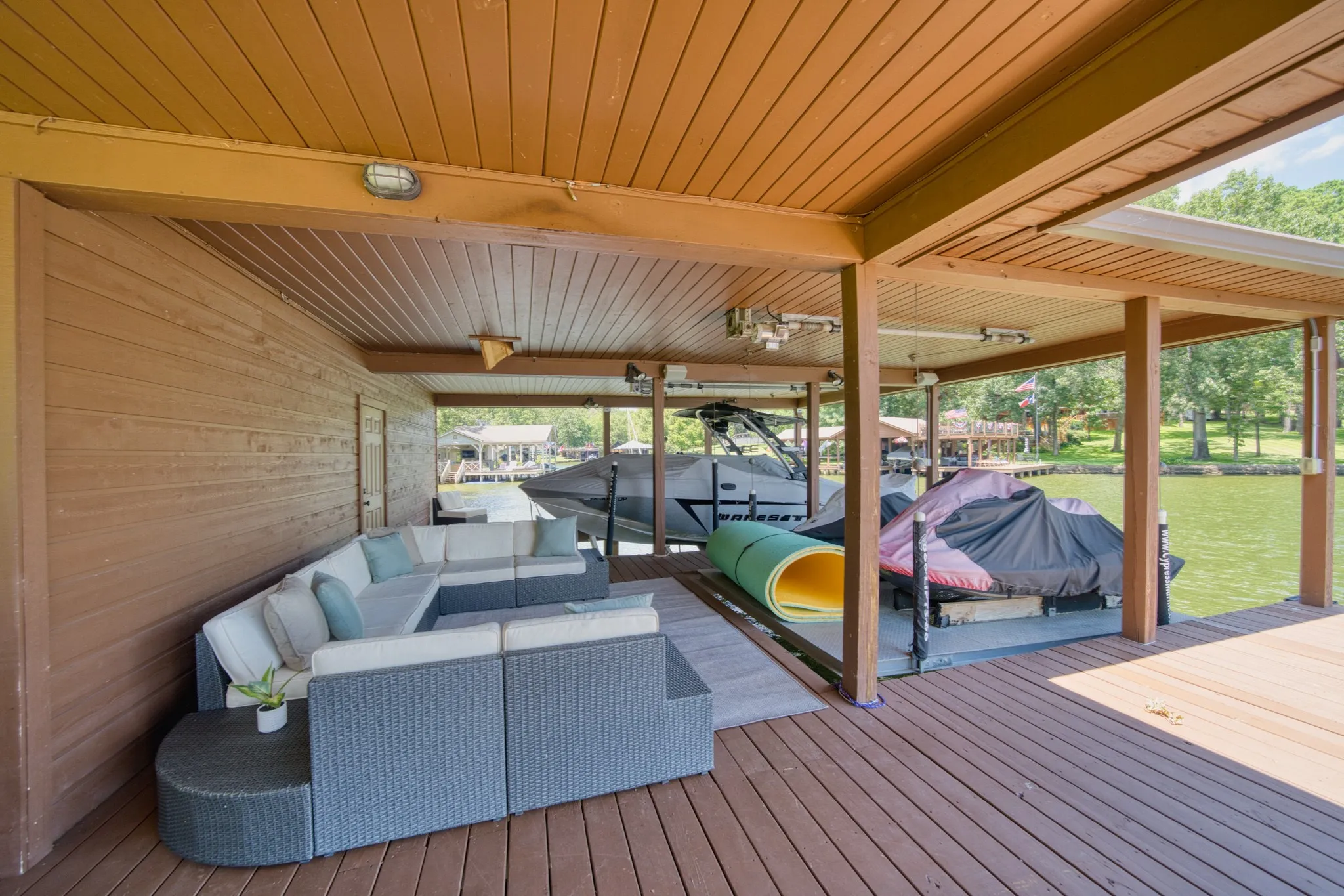 Covered boat dock featuring a wood-finish ceiling, durable deck flooring, and integrated lighting