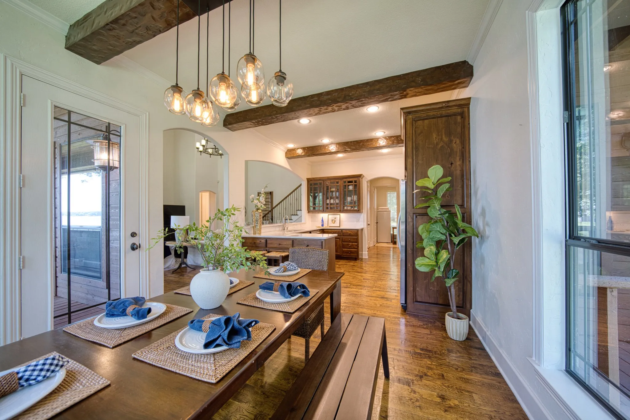 Wood-finish flooring, exposed ceiling beams, a glass-paneled exterior door, and a built-in pantry cabinet