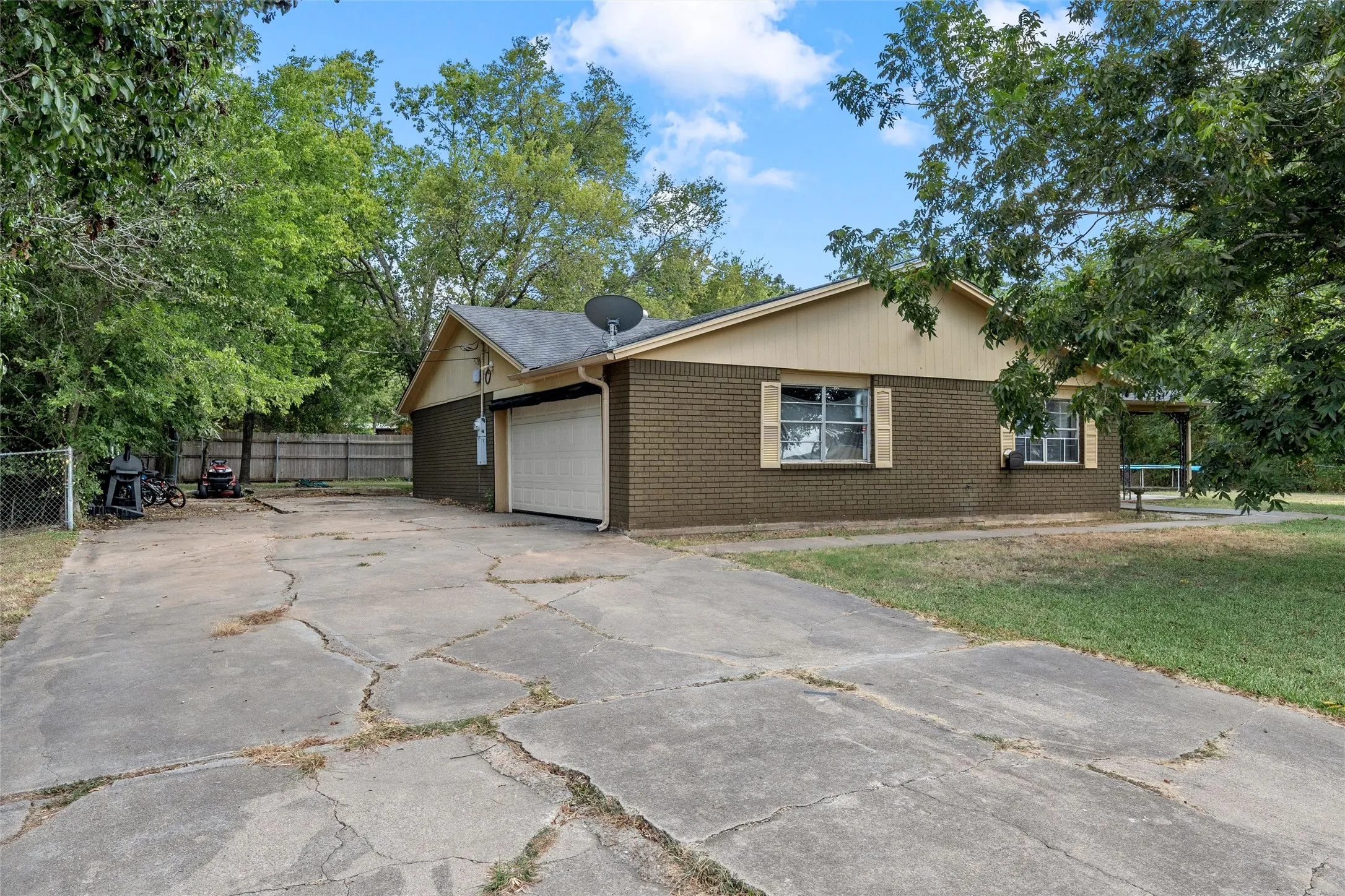 Brick exterior with an attached garage, covered porch, and a fenced backyard