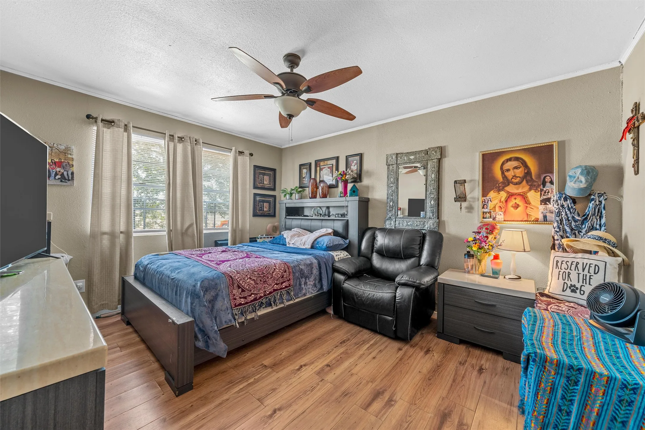 Hardwood-style flooring, ceiling fan with integrated lighting, dual window openings, and neutral wall tones