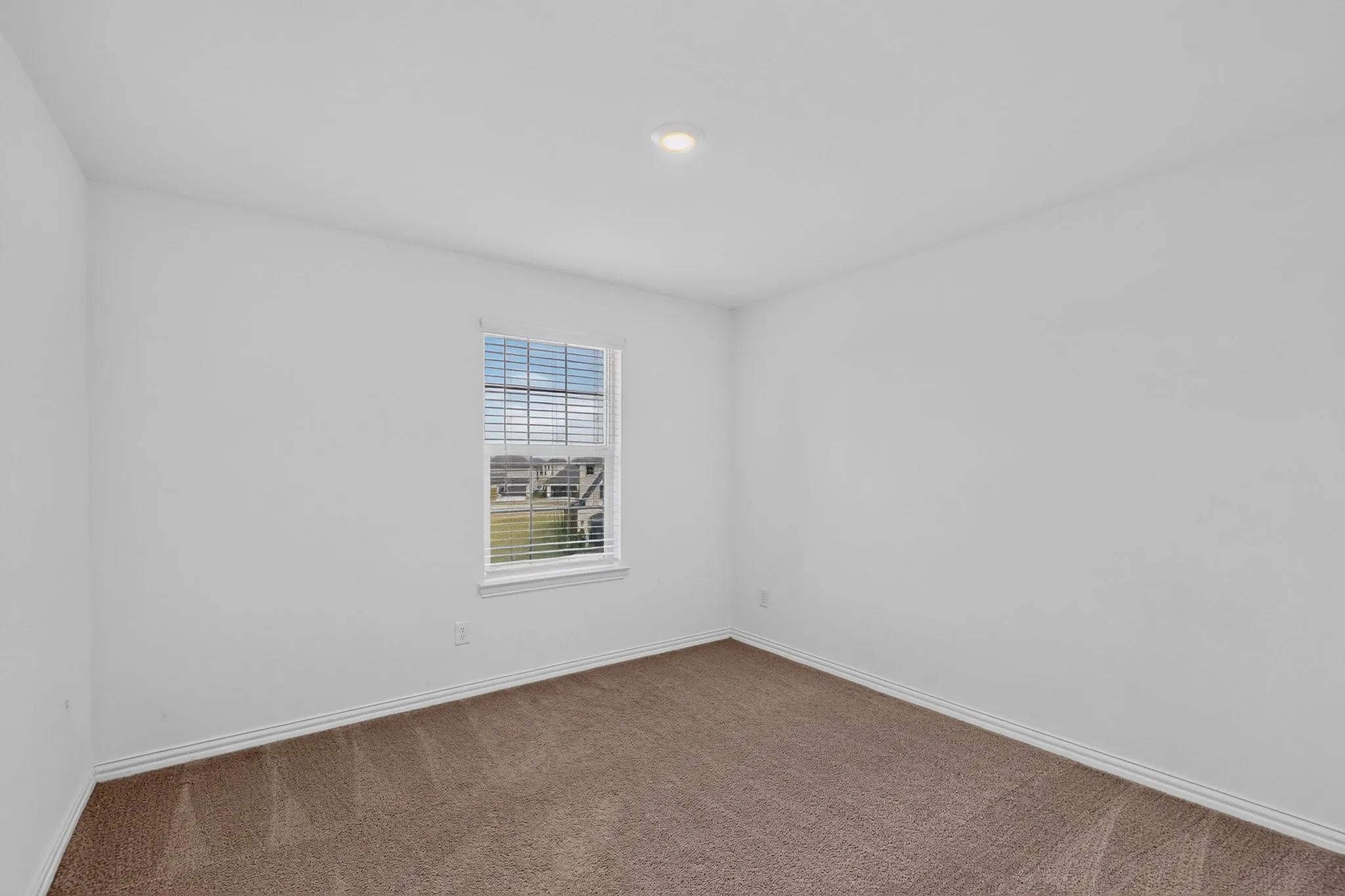 Recessed ceiling lighting, neutral wall paint, single window with blinds, carpeted flooring