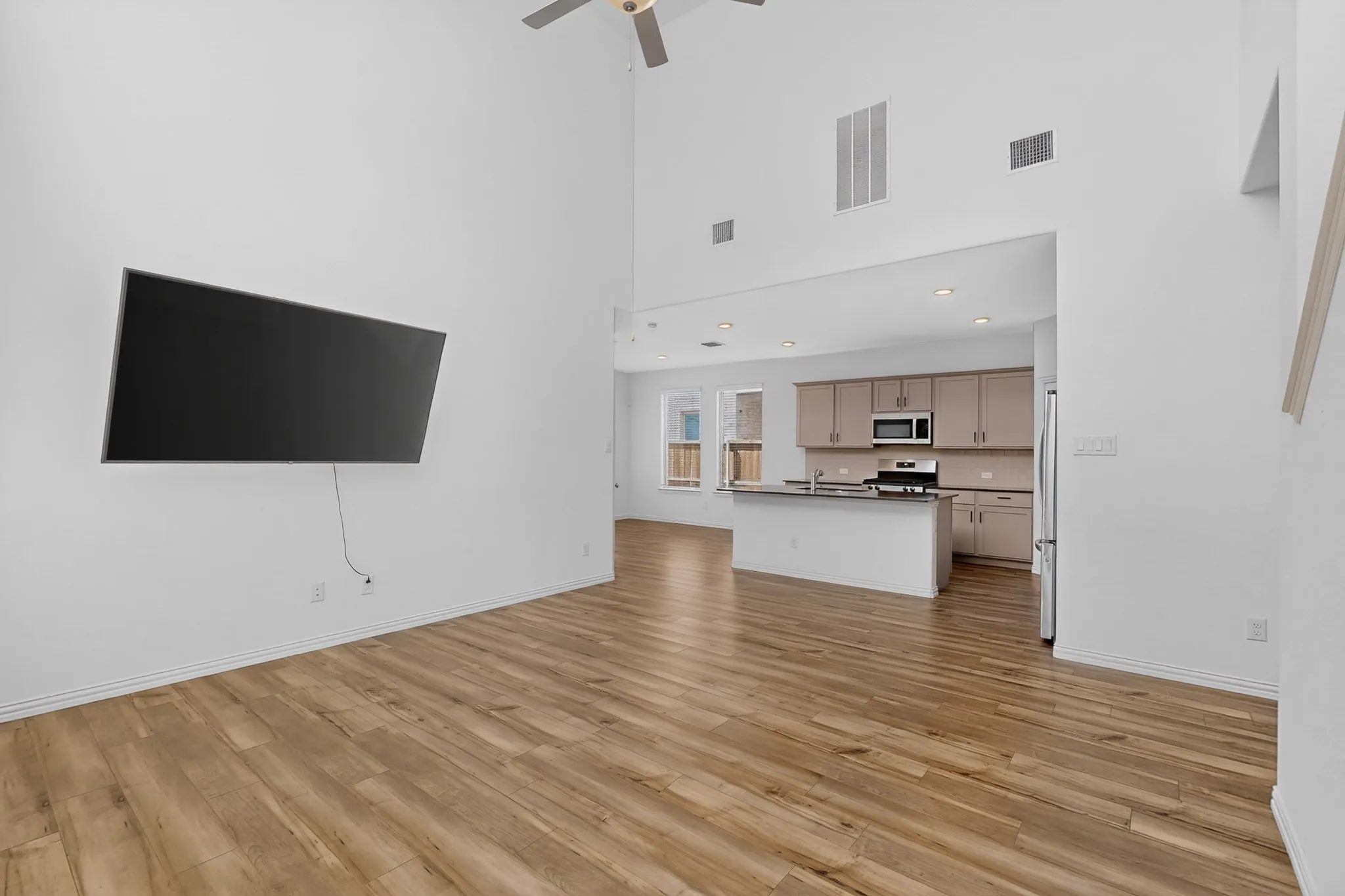 Vaulted ceilings, wood-finish flooring, recessed lighting, ceiling fan, and kitchen with stainless steel appliances